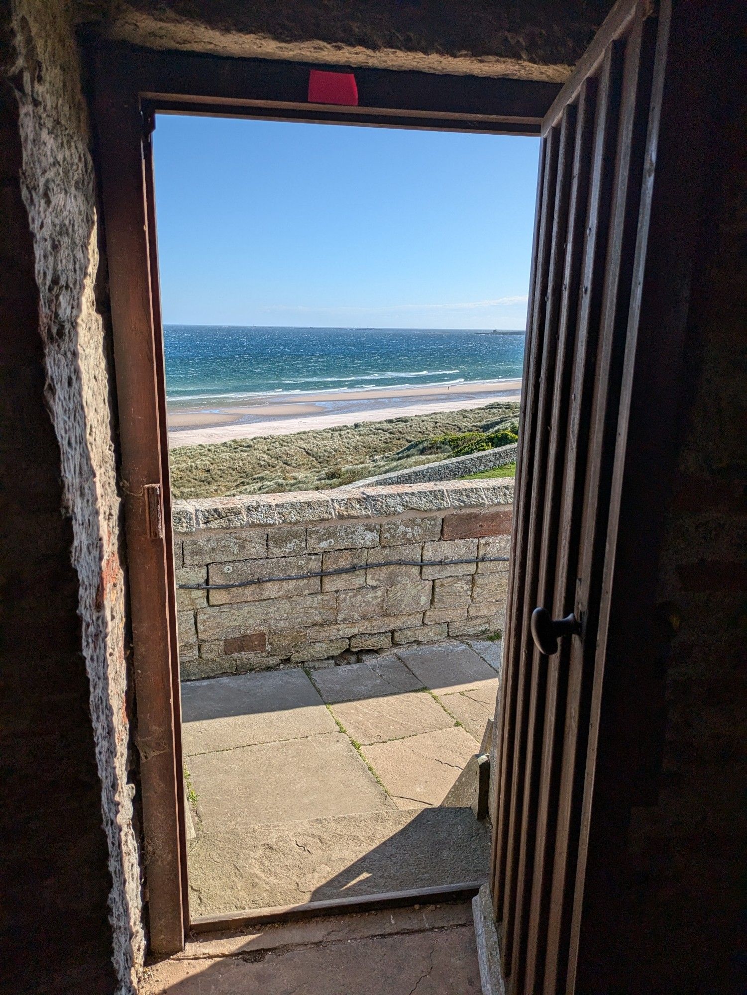 Doorway looking out on to a deep blue sea and beach with blue sky