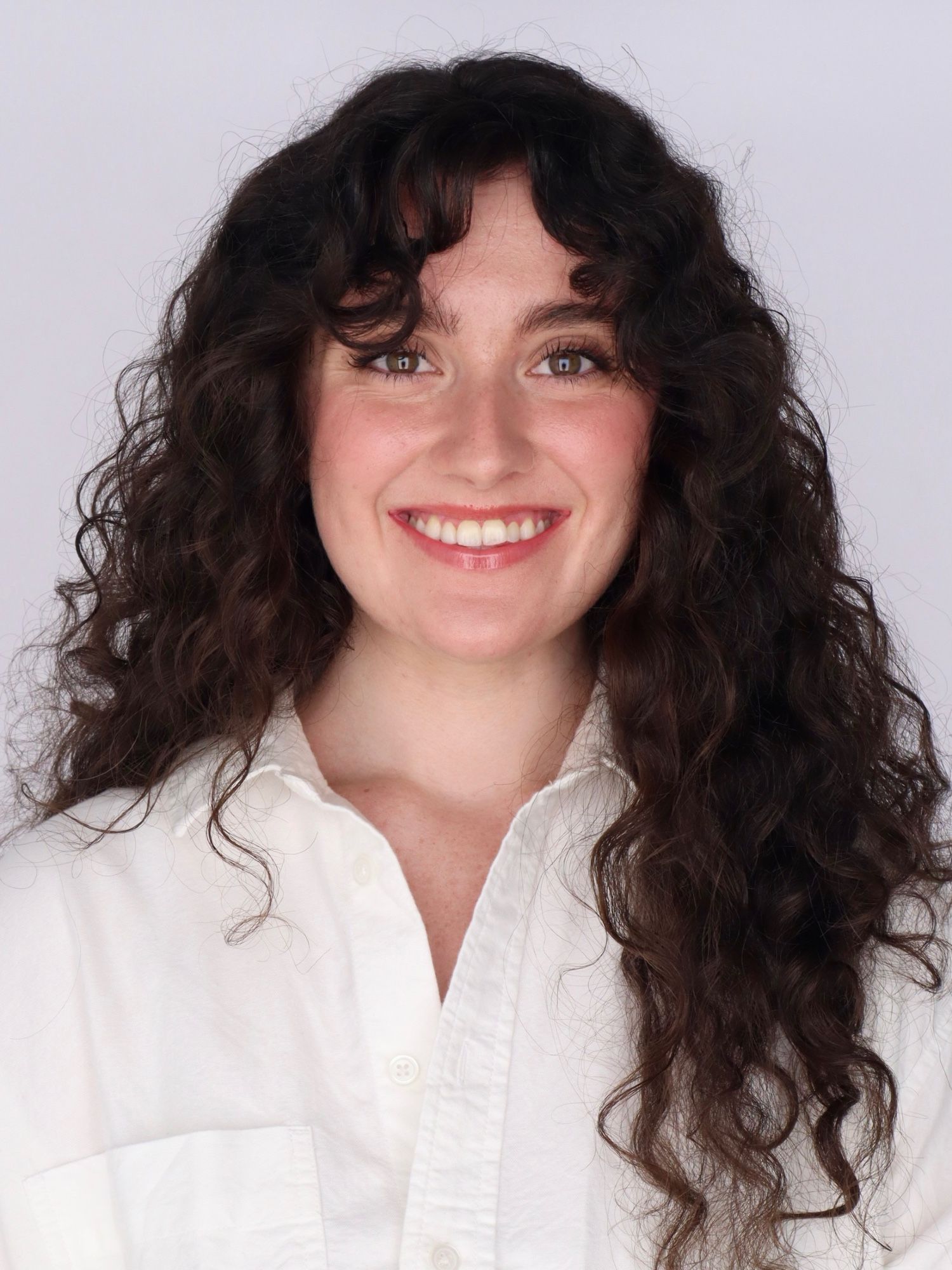 Headshot of woman with long wavy dark brown hair in white blouse