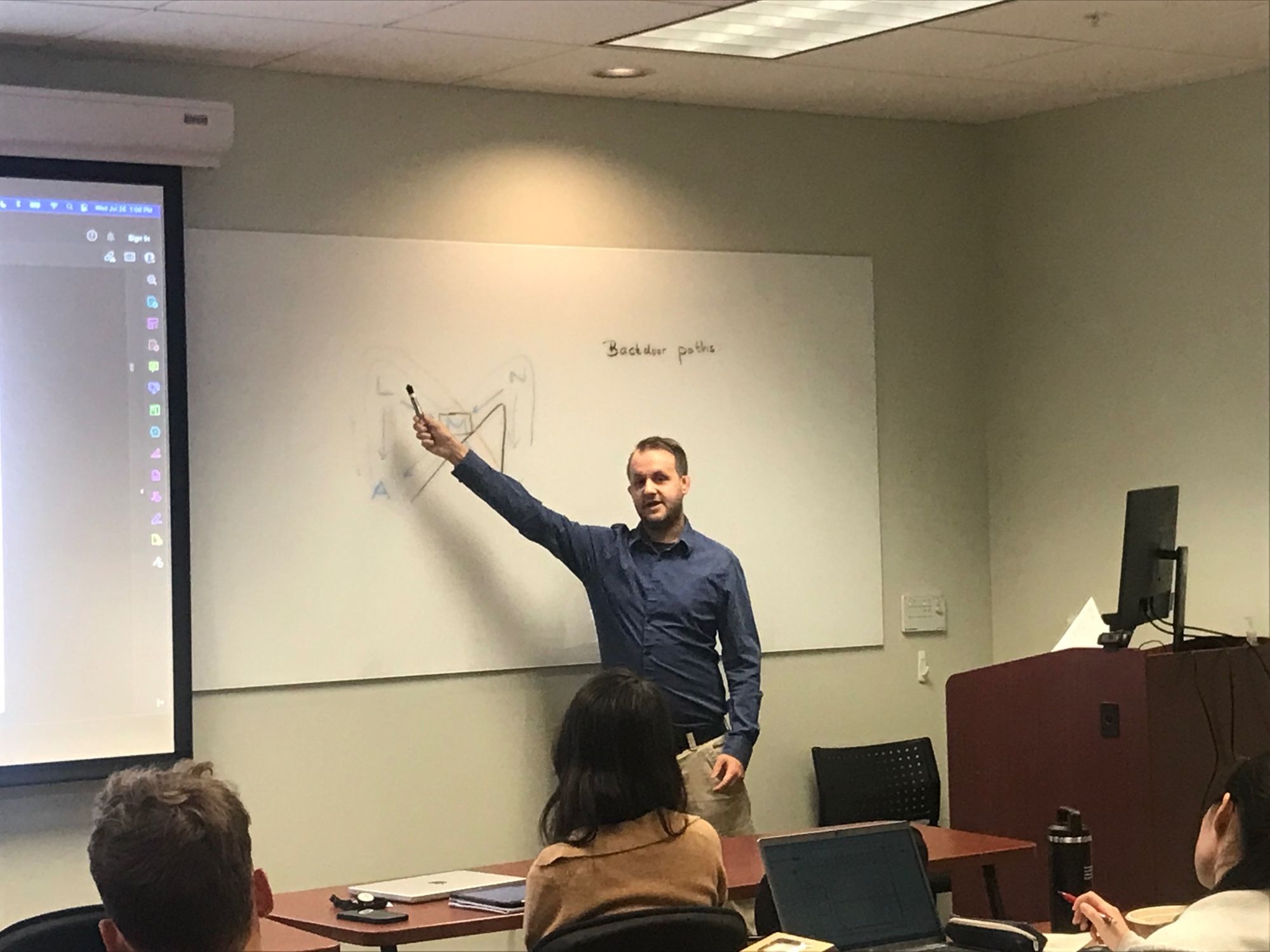 Andrew Spieker gestures to a diagram on a whiteboard during the 2023 Summer Institute