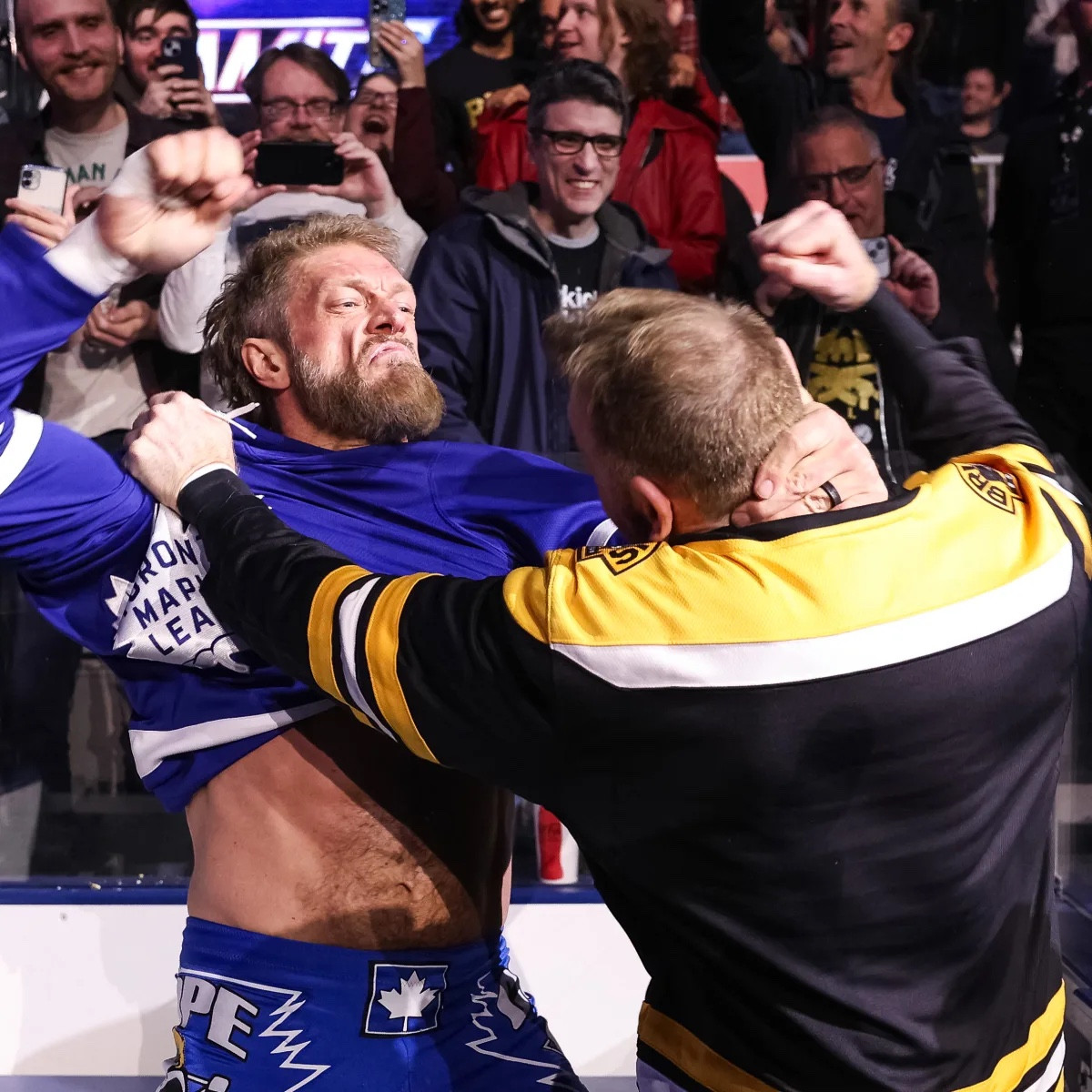 From a recent aew show in their billed hometown of Toronto, Adam Copeland (in a Toronto Maple leafs sweater) and Christian cage (in a Boston bruins sweater) have a hockey fight inside the penalty box of the arena