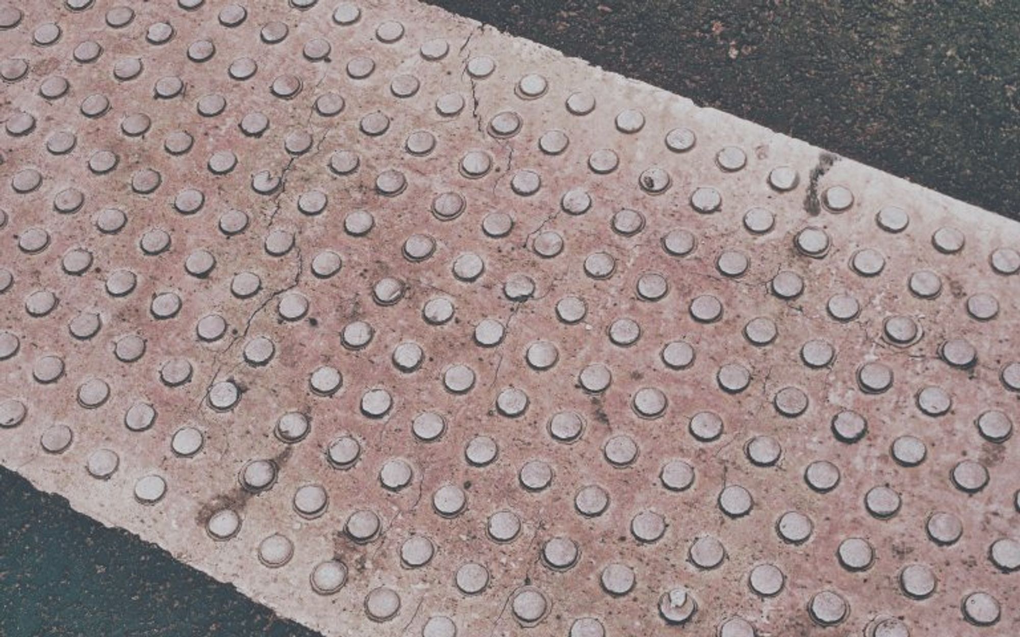 A picture of a dotted podotactile pavement, in great detail, showing the cracks and the texture of the painting