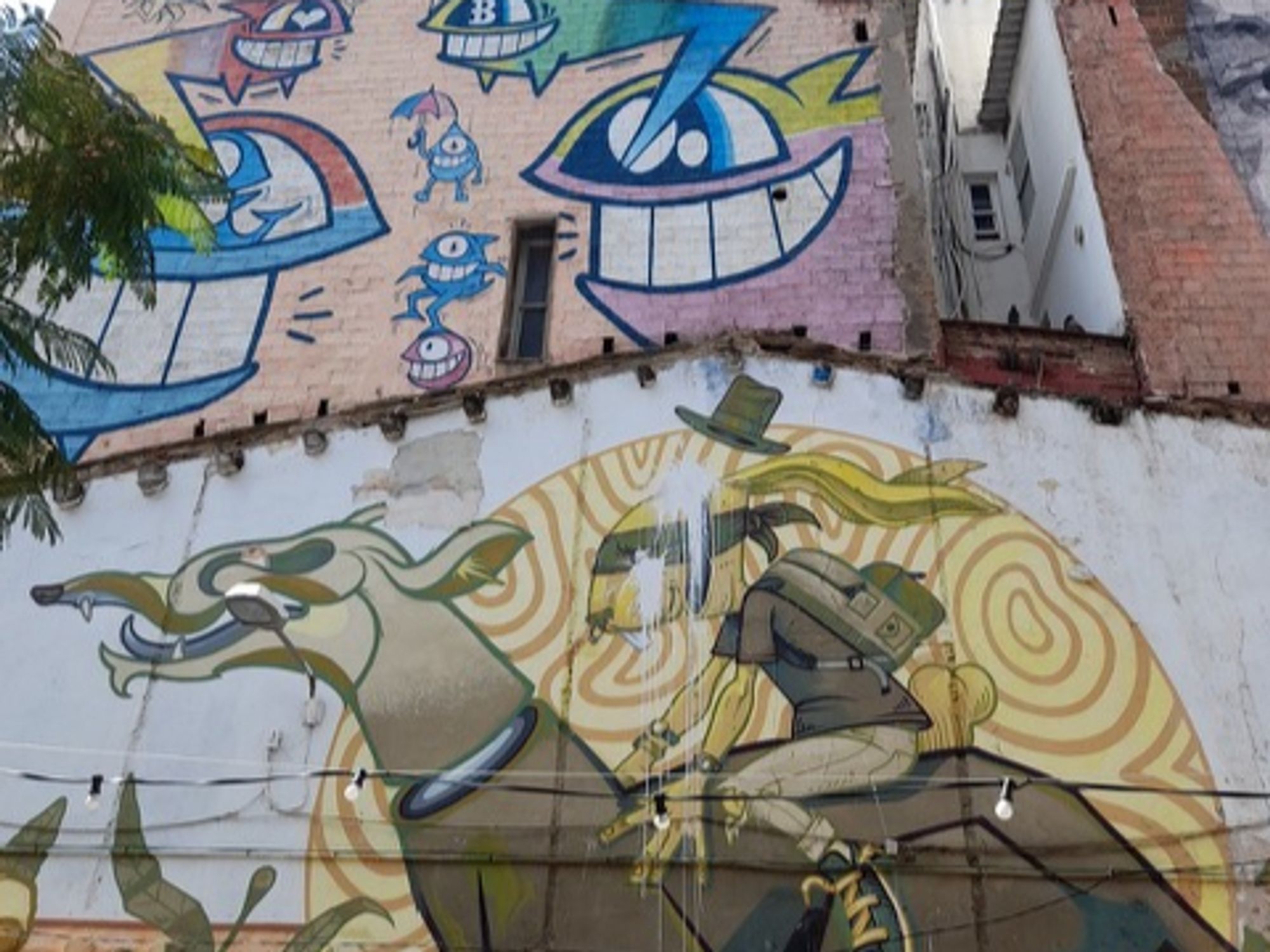 A colourful graffiti on a building in Barcelona, where one can see a bunny dressed in hiking outfit riding what appears to be a psychedelic dog whilst being watched by strange big-eye creatures