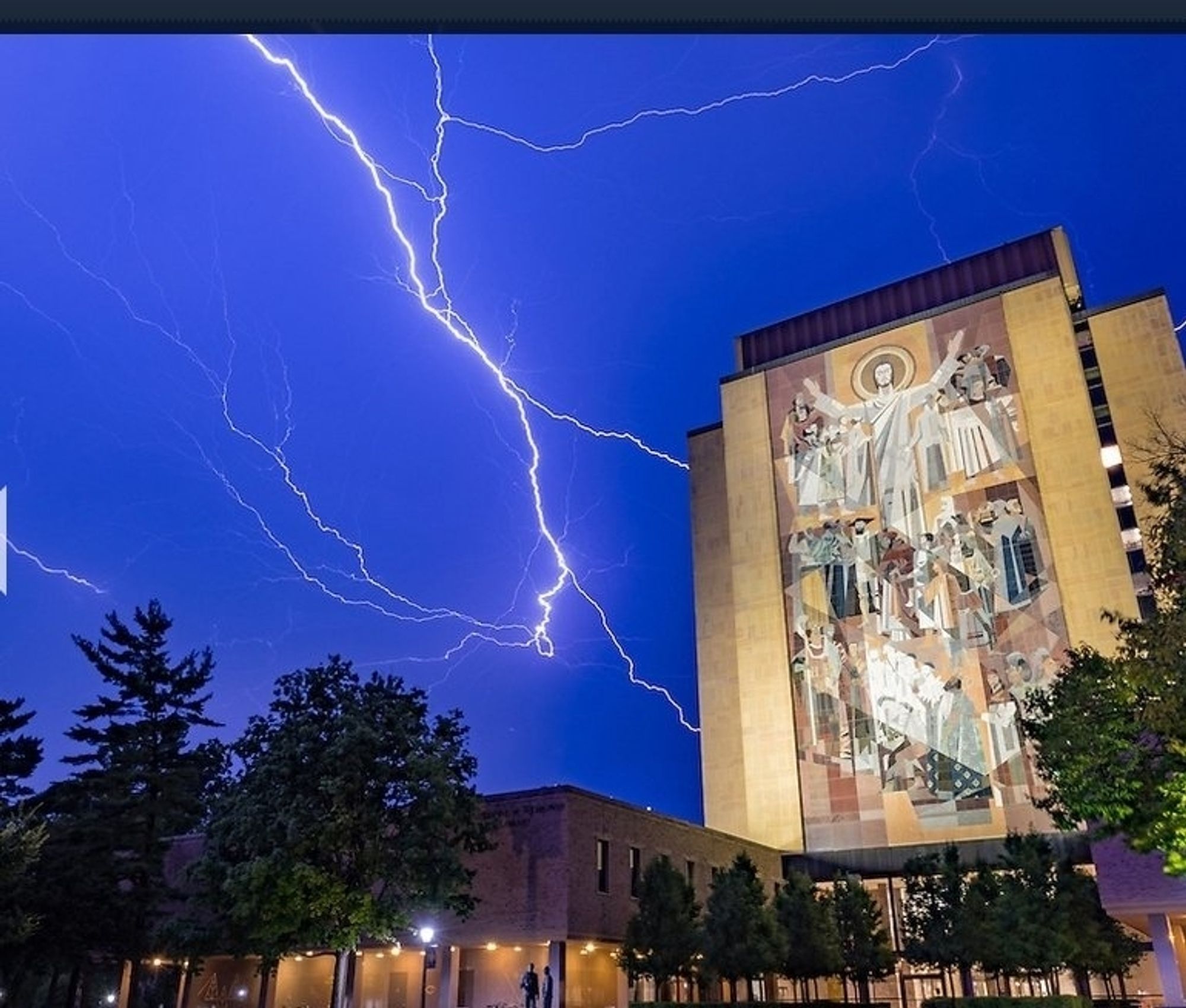 Notre Dame Touchdown Jesus mural, backdropped by lightning strikes