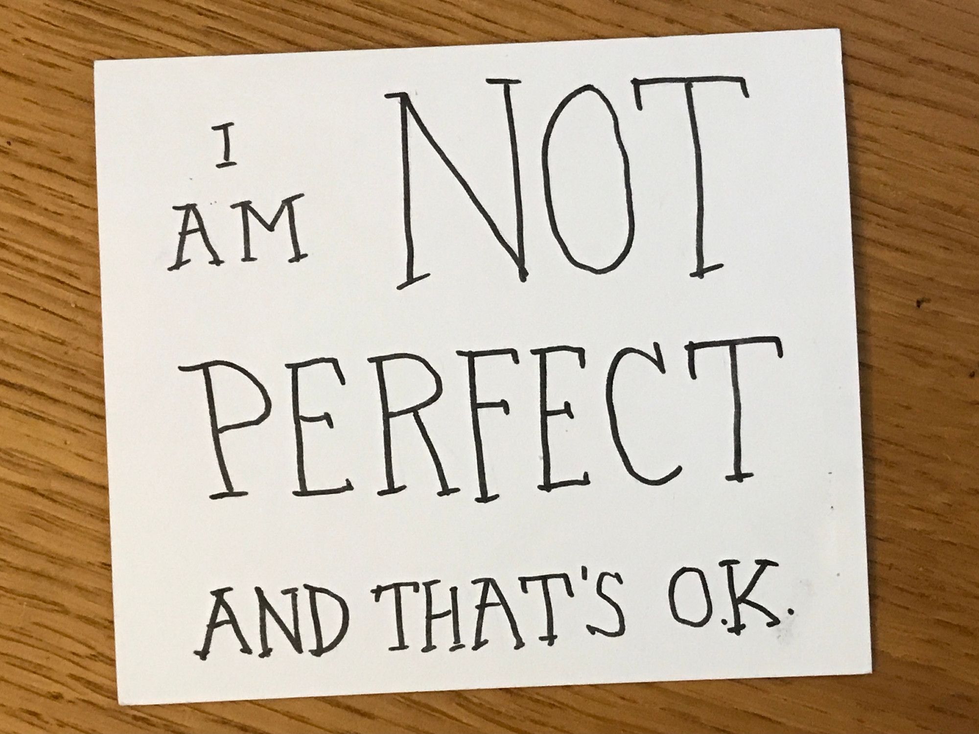 Hand written card in black ink reading "I AM NOT PERFECT AND THAT'S O.K."