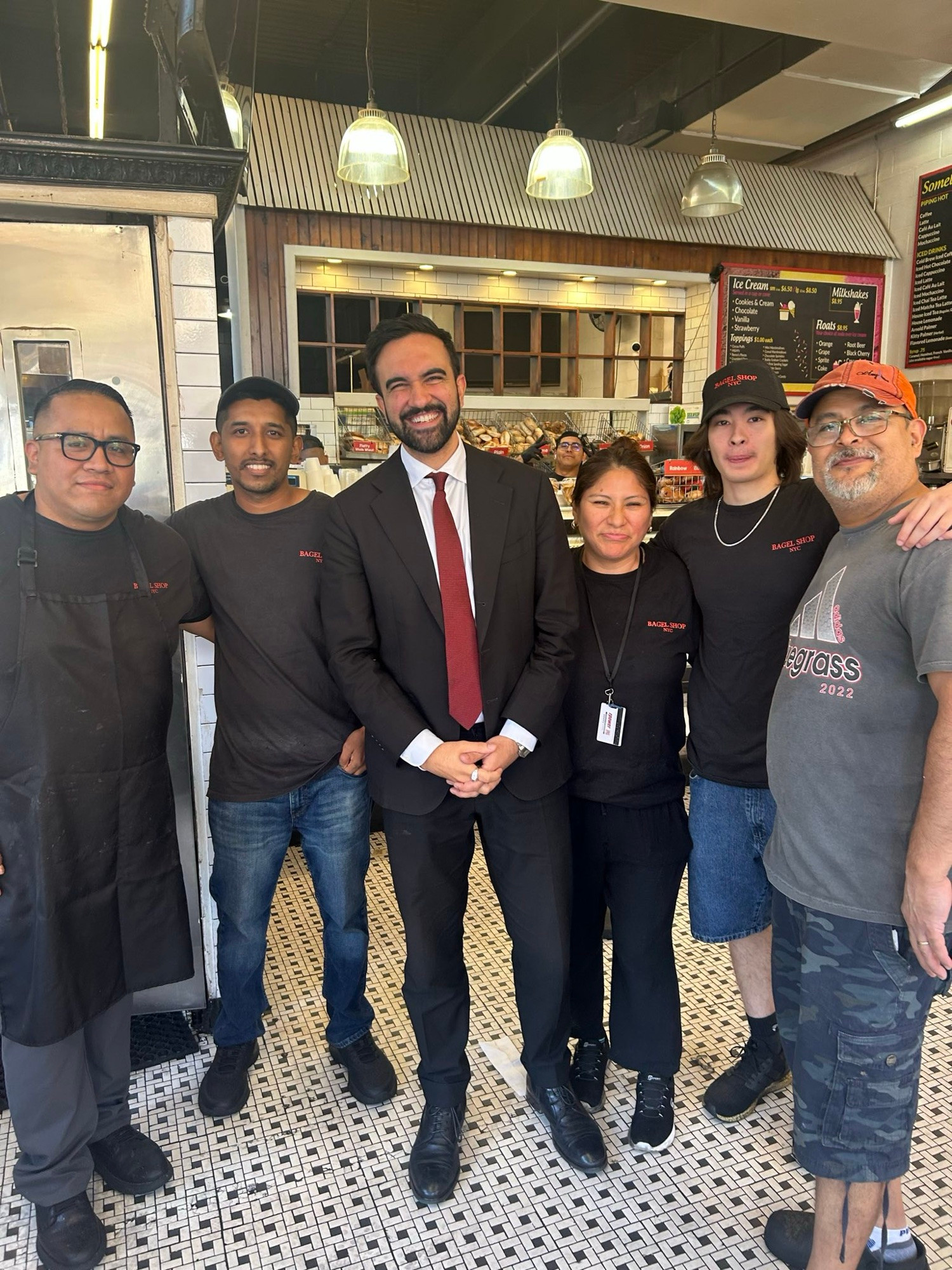 Zohran takes a group photo with the staff of Bagel Shop.