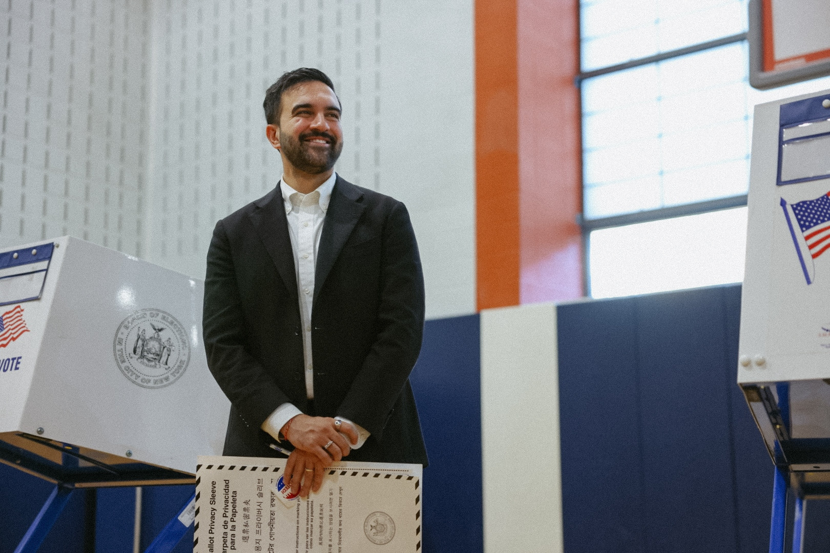 Zohran holding a ballot and smiling. 