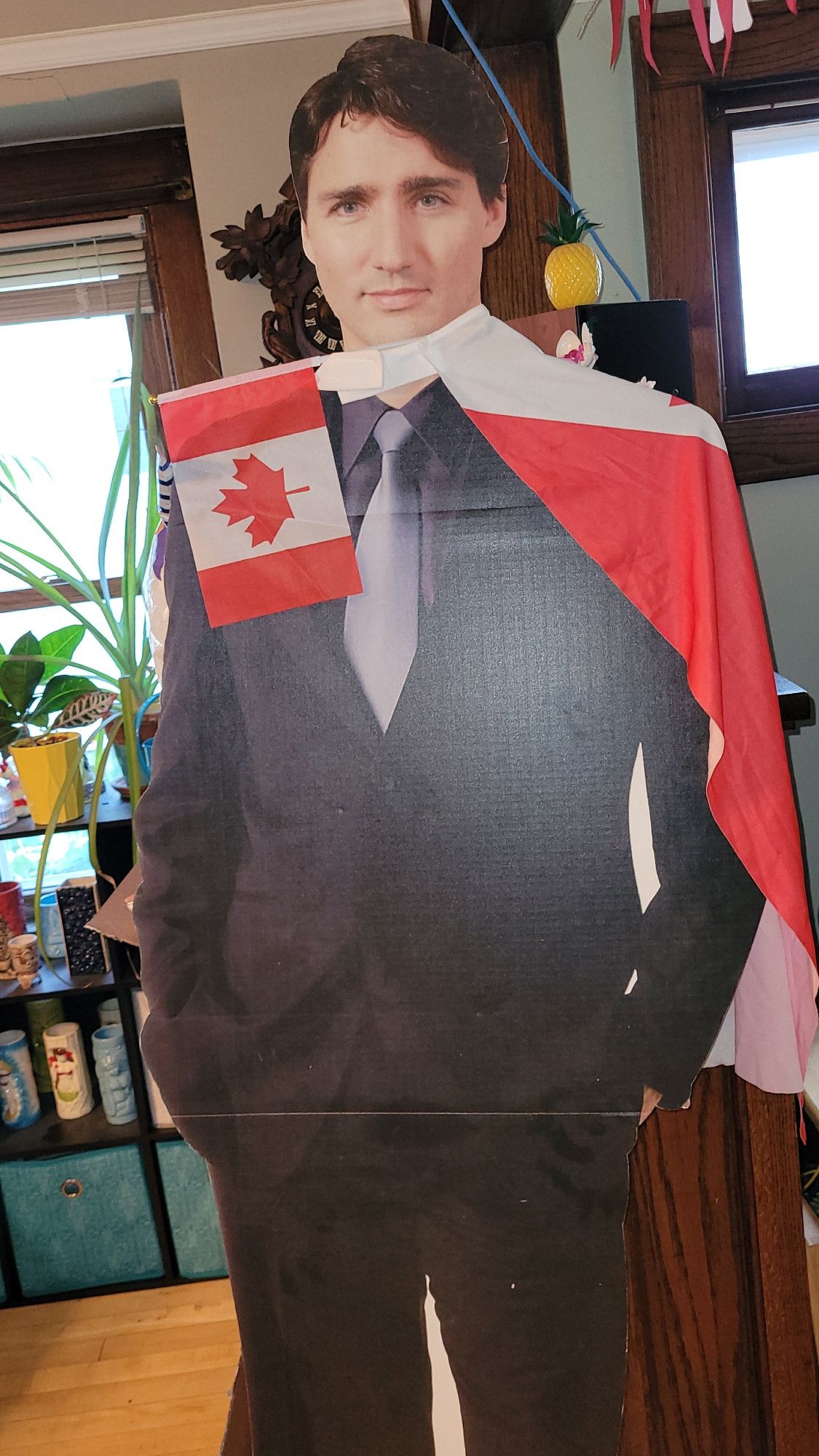 A cardboard cutout of Justin Trudeau, adorned with Canadian flag cape and a smaller Canadian flag sticking out of one of the flag holes.