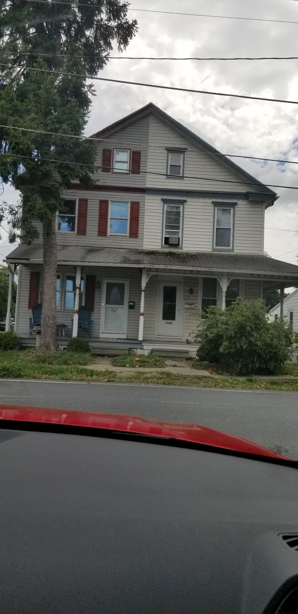 Two-family house with everything different: siding, window alignment, shutters, colors, roofs, porch posts.