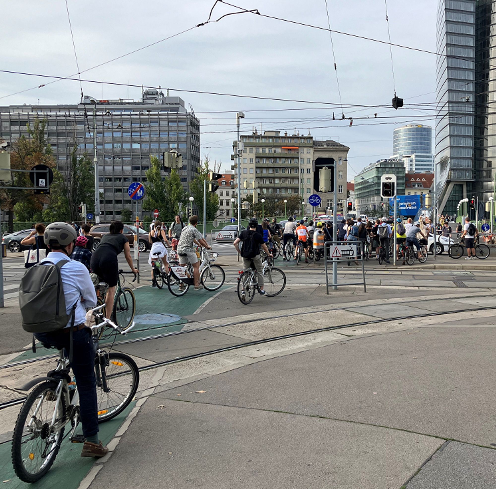 Foto von vielen Radfahrerinnen und Radfahrern, die vor roter Ampel warten