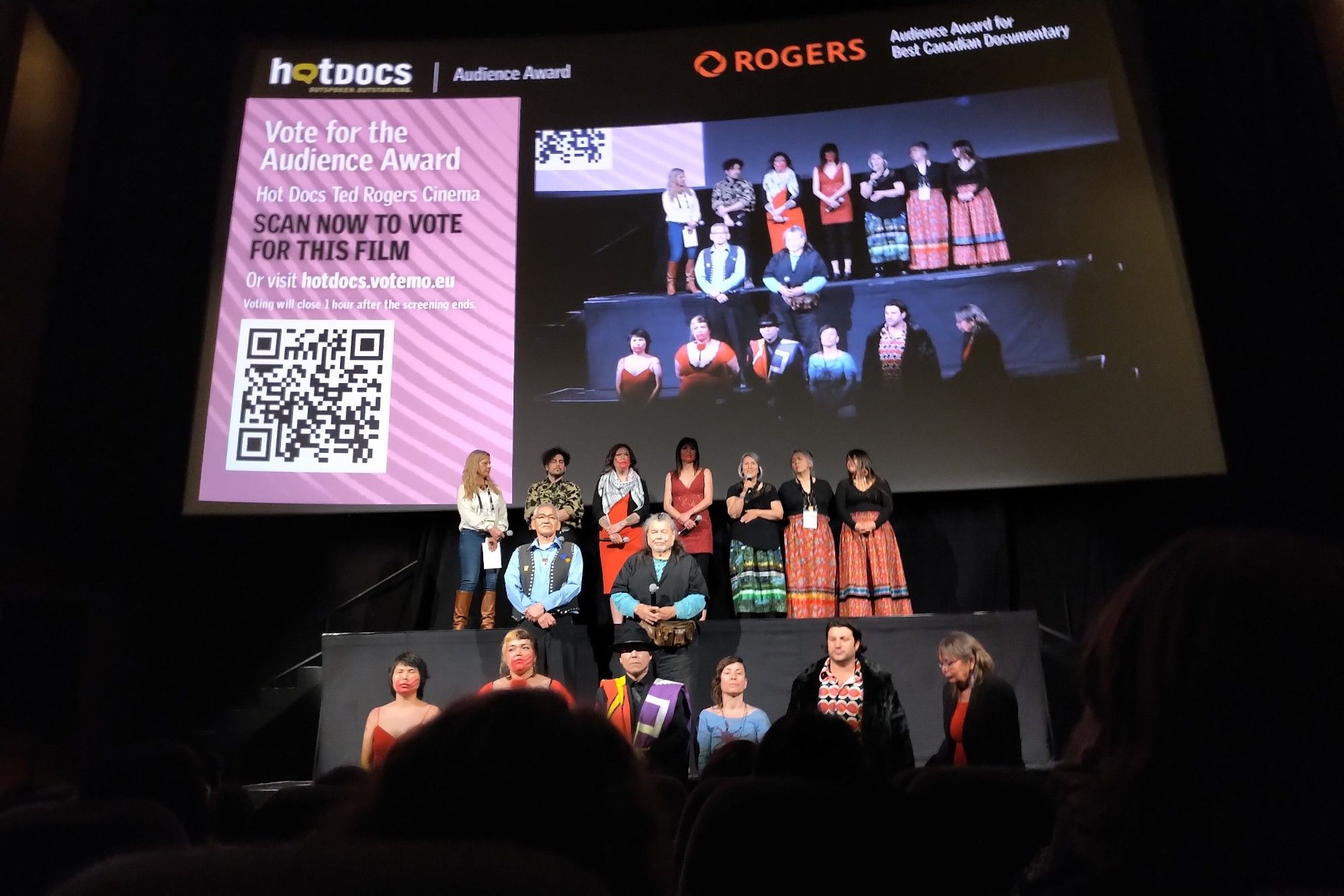 A pic of the stage at the Bloor Cinema following the screening of Yintah, the risers lined by Wetʼsuwetʼen land defenders and their allies.