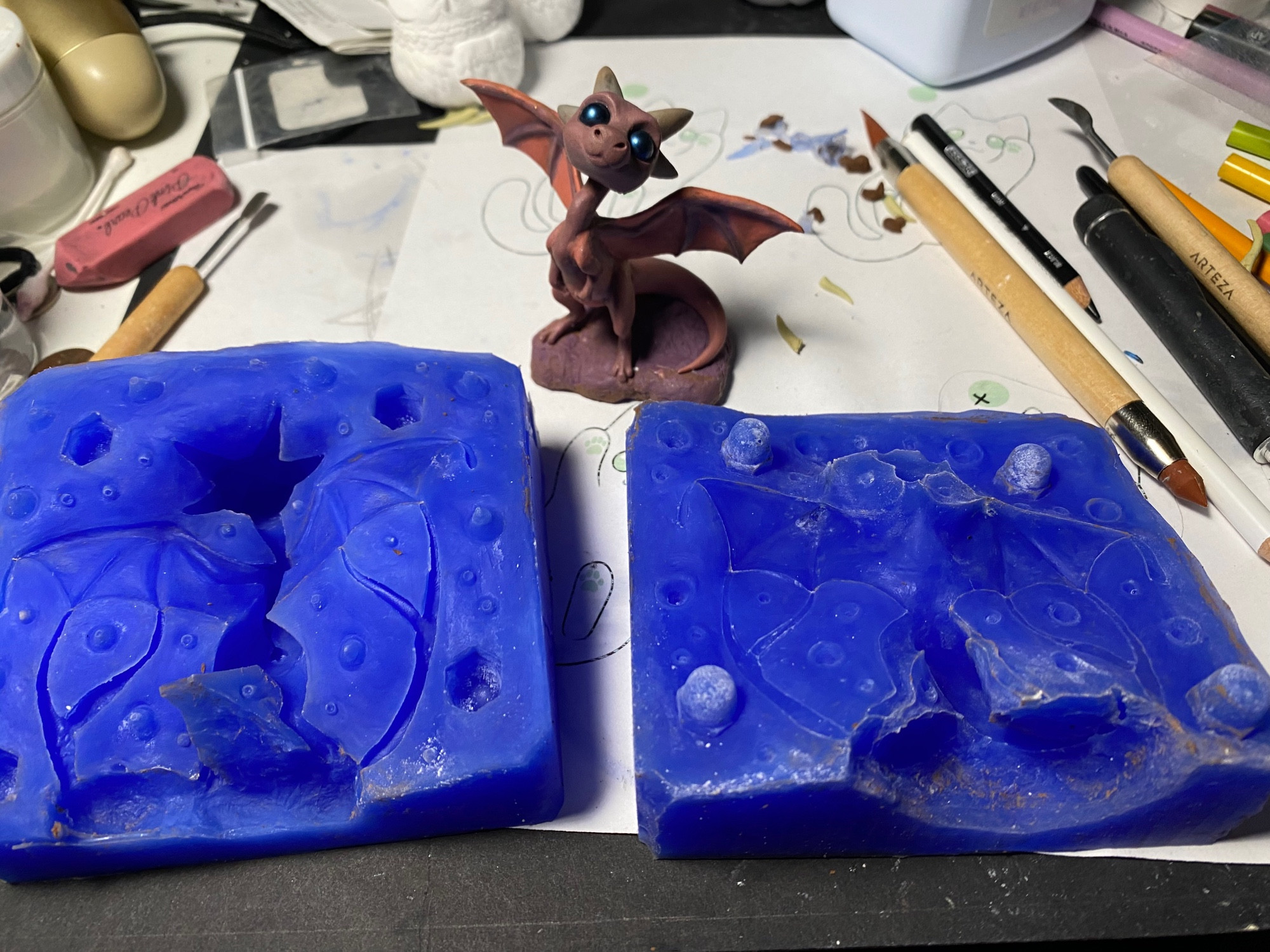 A chibi dragon sculpture and the two-part mold created with it.