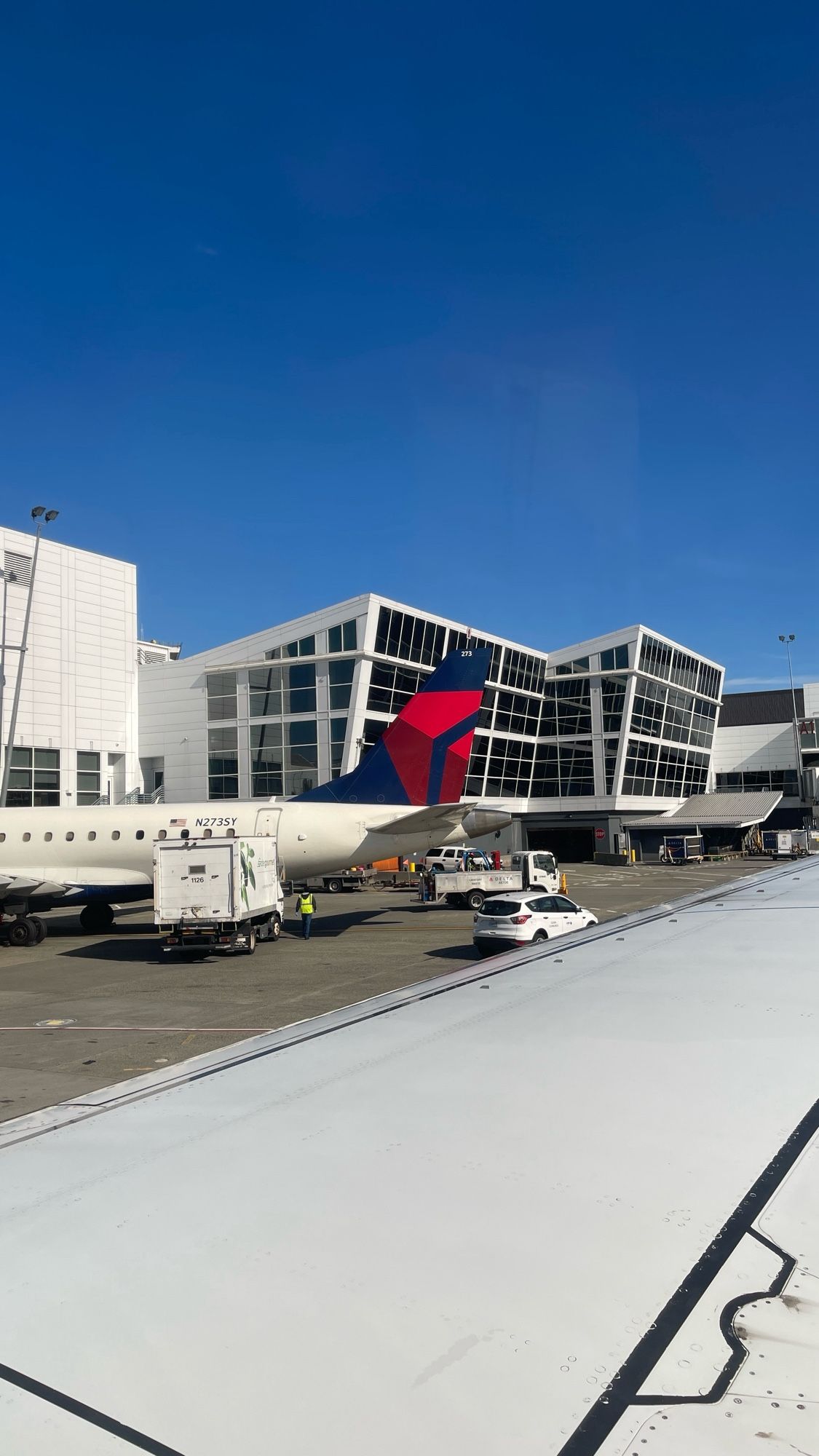 Image shows part of the wing of a plane with another plane in the background with the Delta airlines logo on the tail