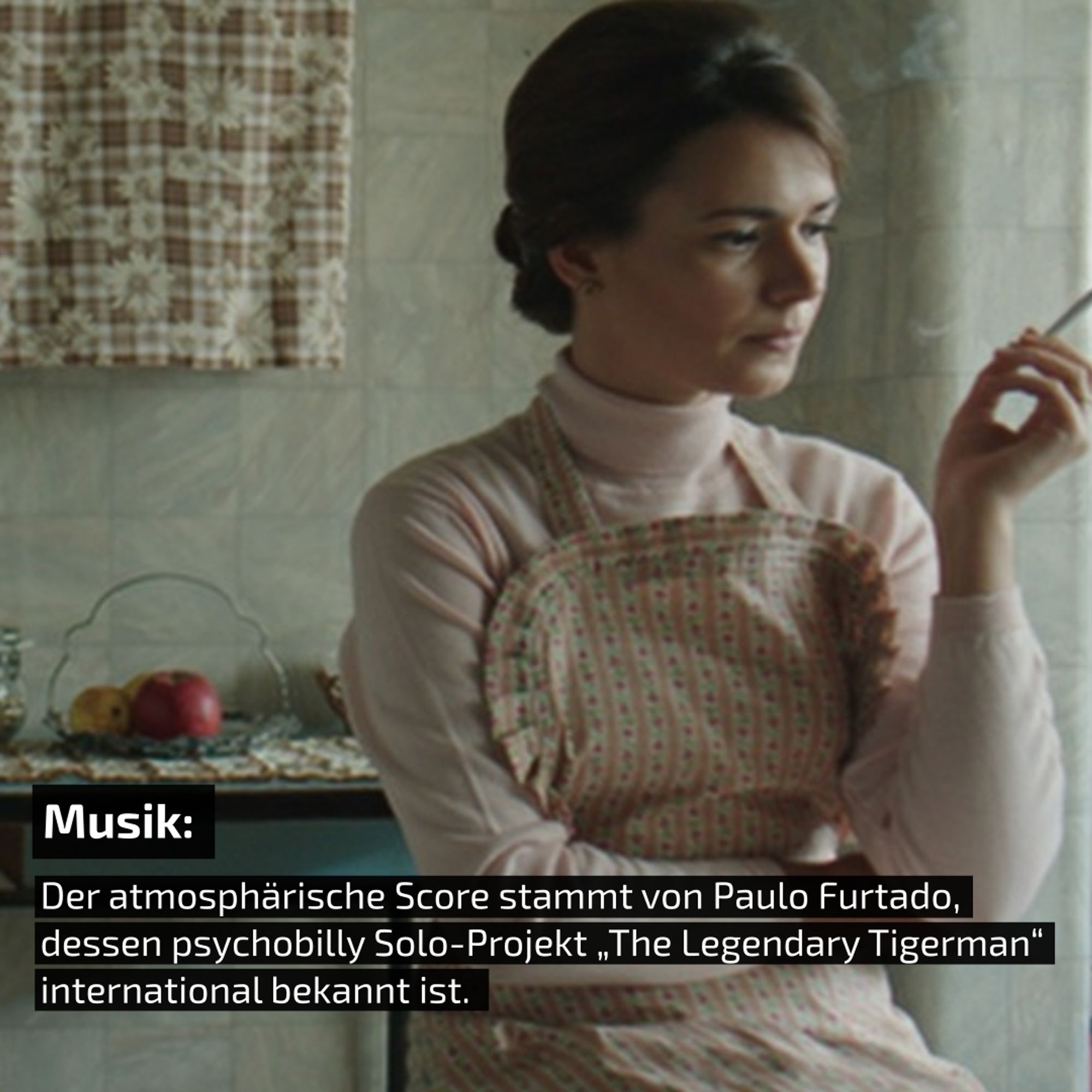 Szene aus dem Kurzfilm "Menina". Vortsetzung des Bildes aus dem vorherigen Bild. In diesem Teil der Küche steht die junge Frau. Sie trägt einen Kittel und raucht am Fenster. Ein Text erklärt, dass "The Legendary Tigerman" die Musik zum Film komponiert hat.