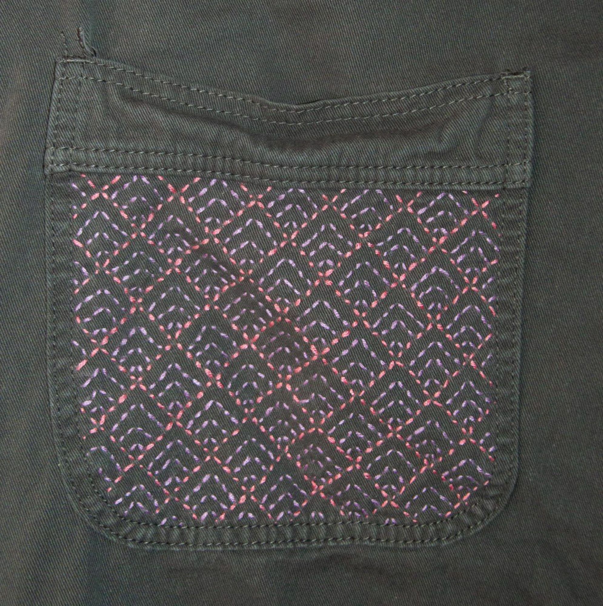 A detail of an embroidery on a overall inspired by the Ajiro pattern of the Japanese Sashiko style