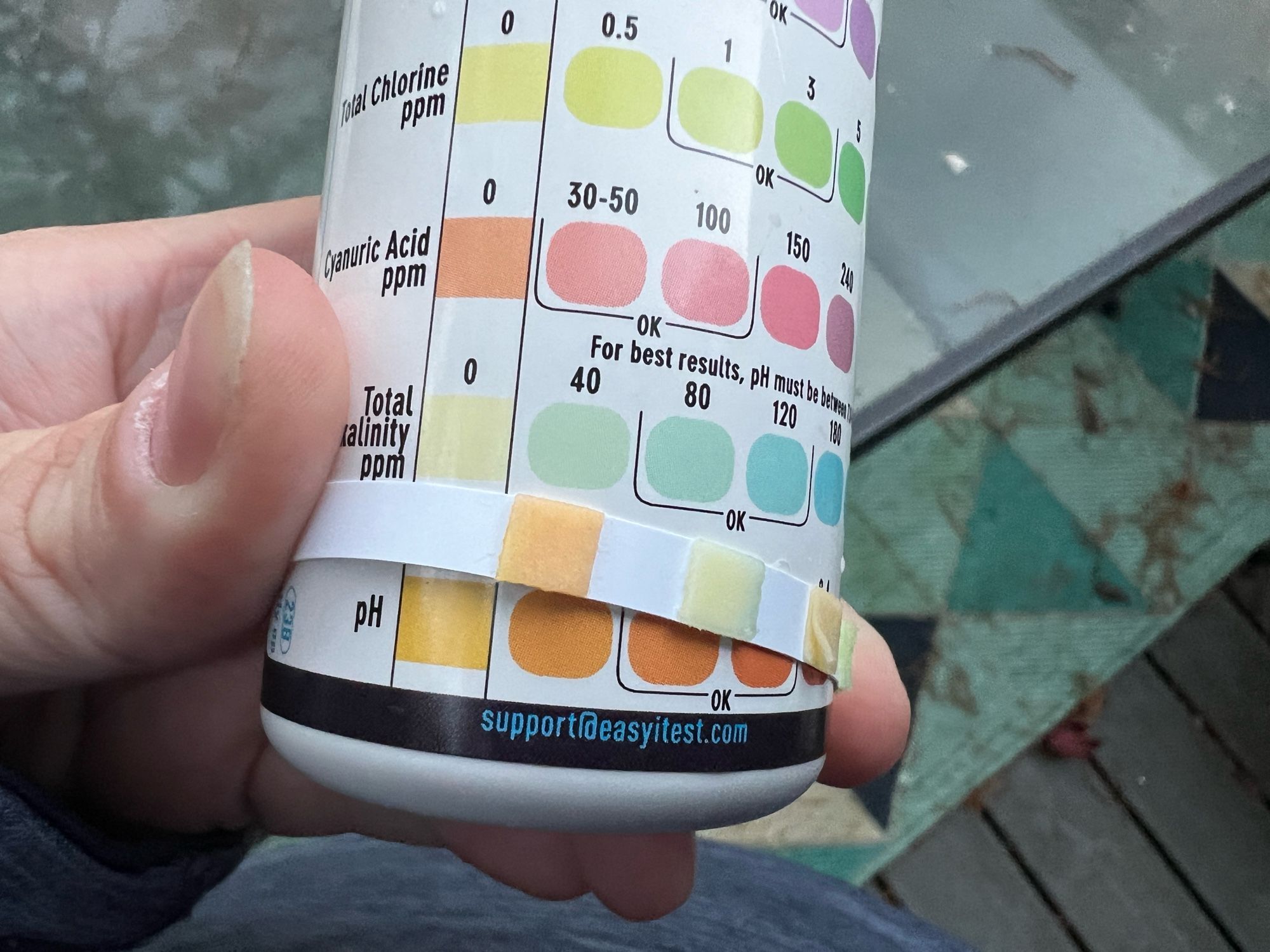 A light orange test strip square matching up to the light orange indicator stating pH levels are low.