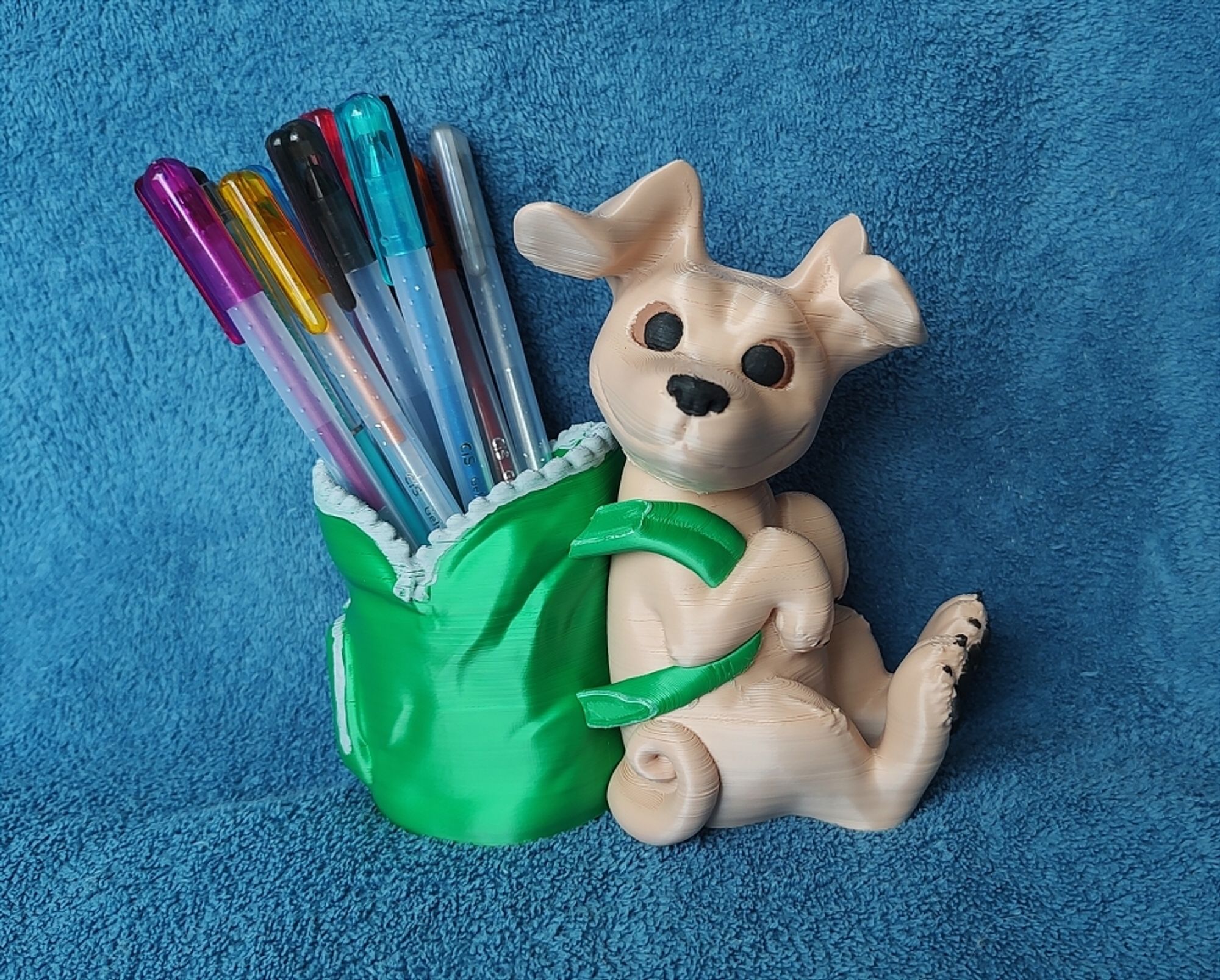 Photo of a 3D printed dog, sitting down using a backpack, the bag is open at the top where the pencils go.