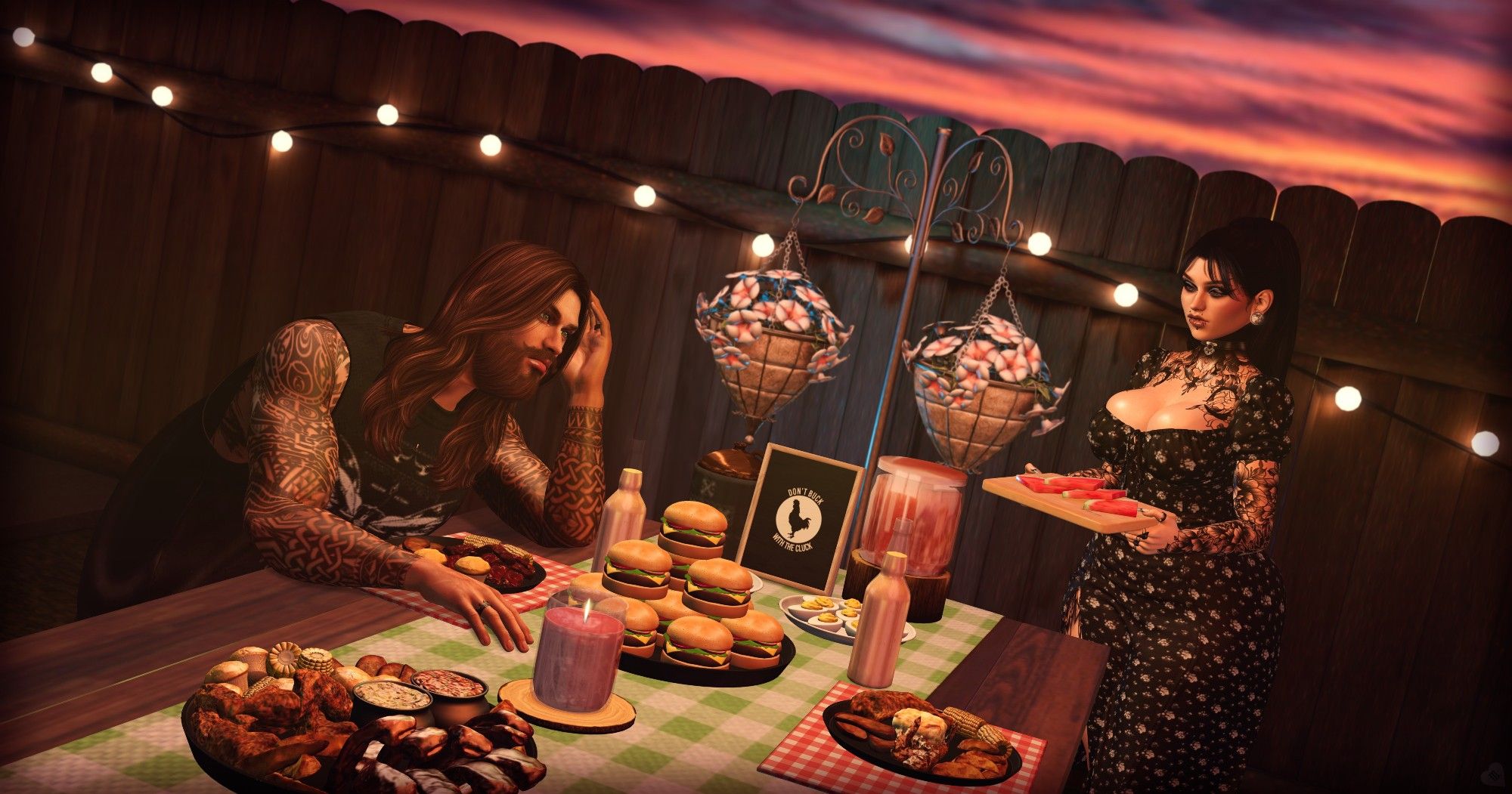 A man with long brown hair sitting at a picnic table that has a vast variety of food. A woman stands to the right side of the end of the table with a platter of watermelon slices in her hands as she pauses to put them on the table.