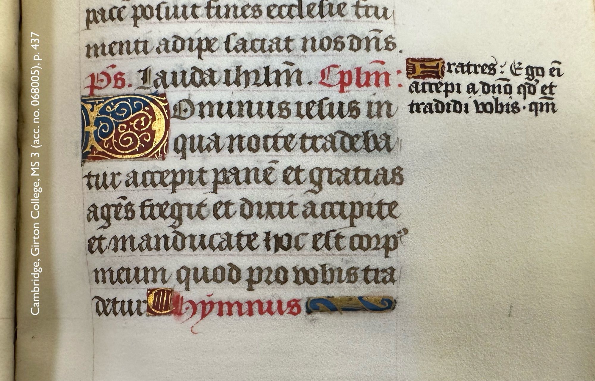 Detail of a parchment leaf in a medieval manuscript: page 437 in Girton College, manuscript 3. Visible are 10 lines of Latin text copied mostly in black with a few words in red, and ornamented with 2 illuminated initials: a small paragraph symbol in gold on a burgundy ground, and a letter ‘D’, 2 lines high, rendered in gold on a square ground divided diagonally into dark blue and dark red. In the right margin, another hand has added in a bit of text skipped during the original copying of the page: 3 very short line of Latin text opening with a tiny illuminated initial ‘F’ rendered in gold atop a burgundy ground.