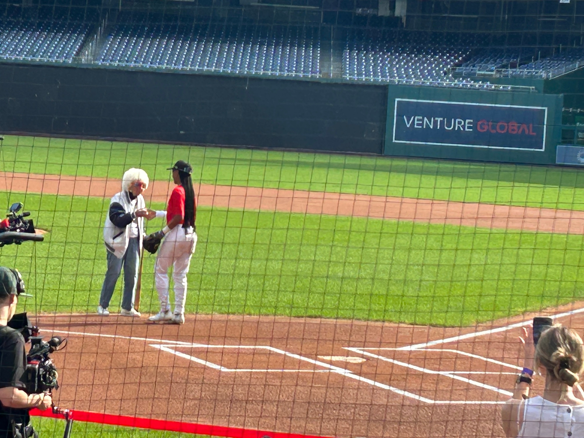 Maybelle Blair and Mo’Ne Davis shake hands just in front of home plate after Blair throws out first pitch. 