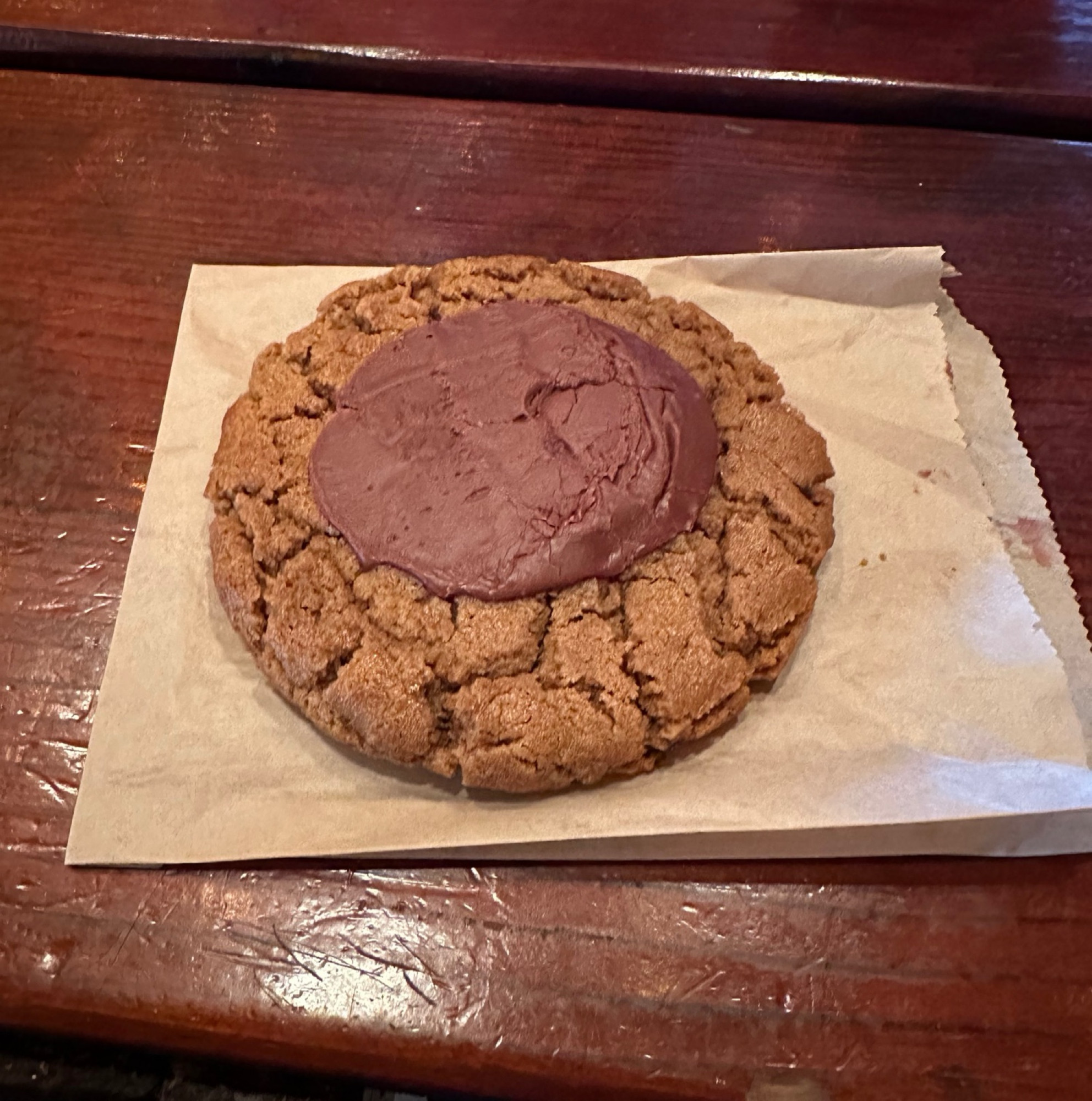 A huge peanut butter cookie with a dollop of chocolate on top