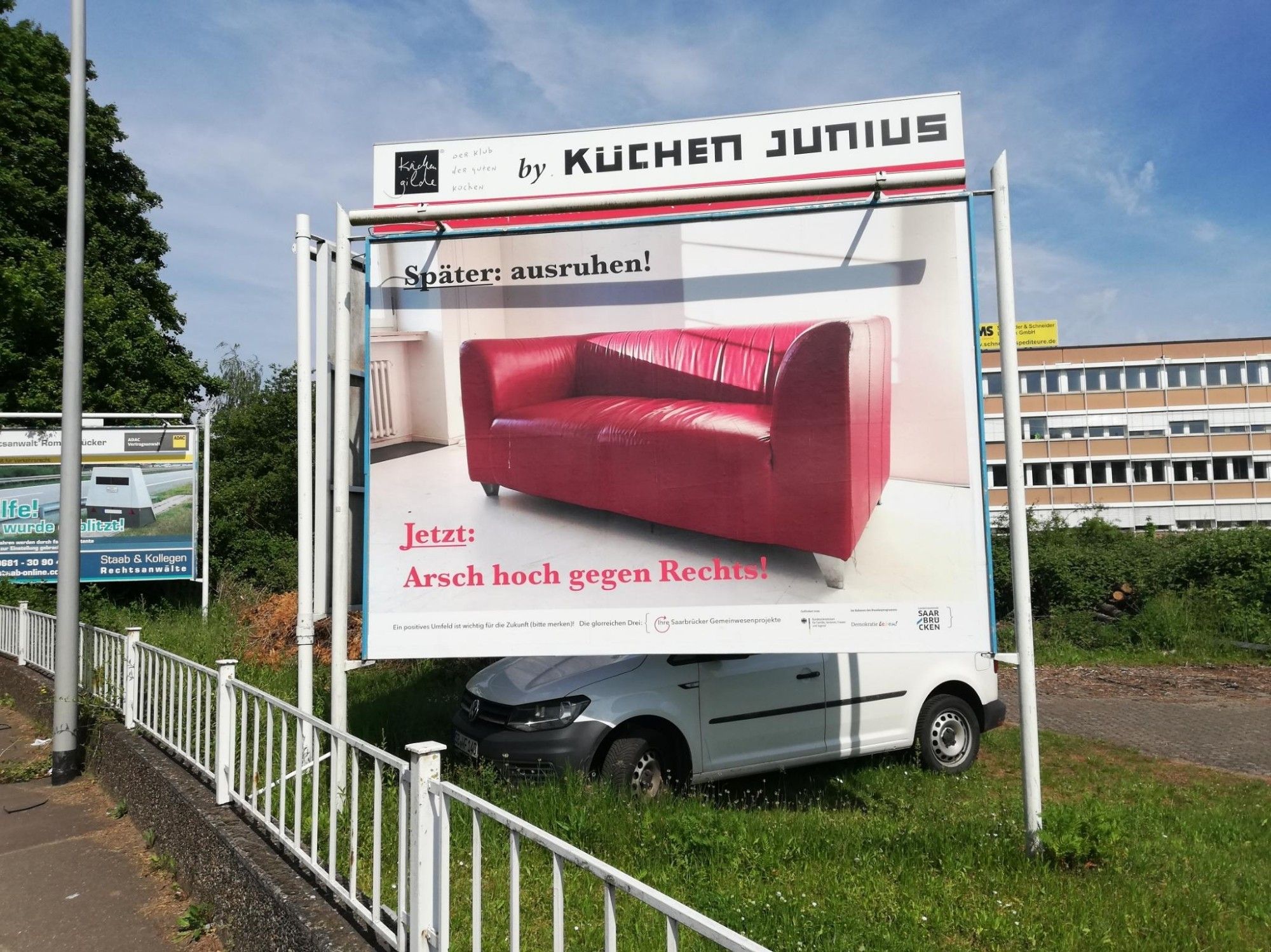 In einem hellen Raum steht ein rotes bequem aussehendes Ledersofa. Dazu die Schrift: 
Später ausruhen.
Jetzt Arsch hoch gegen Rechts!
Darunter steht kleingedruckt: 
Ein positives Umfeld ist wichtig für die Zukunft! Die glorreichen Drei.