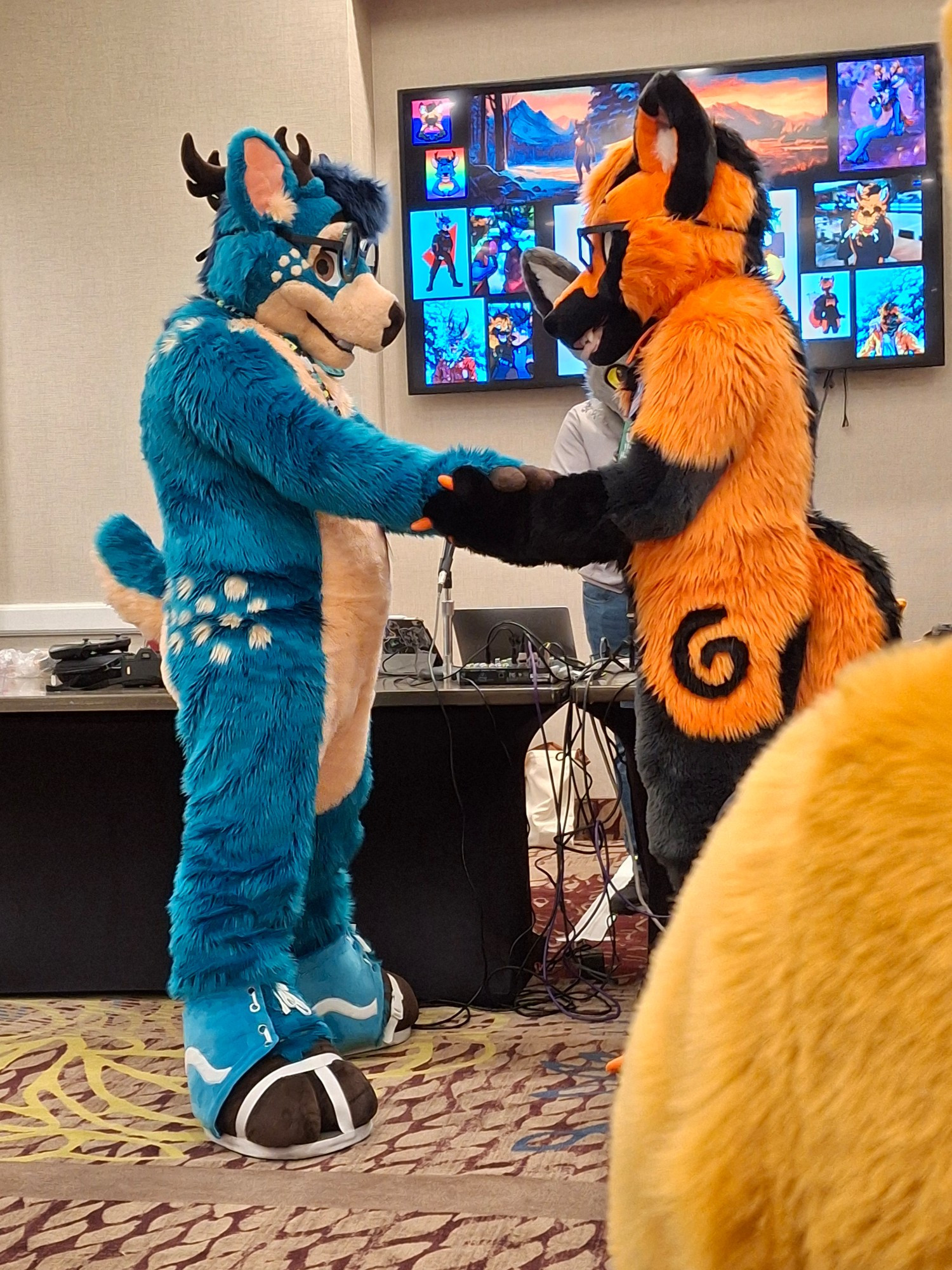 A blue deer and an orange-and-black fox looking at each other holding paws