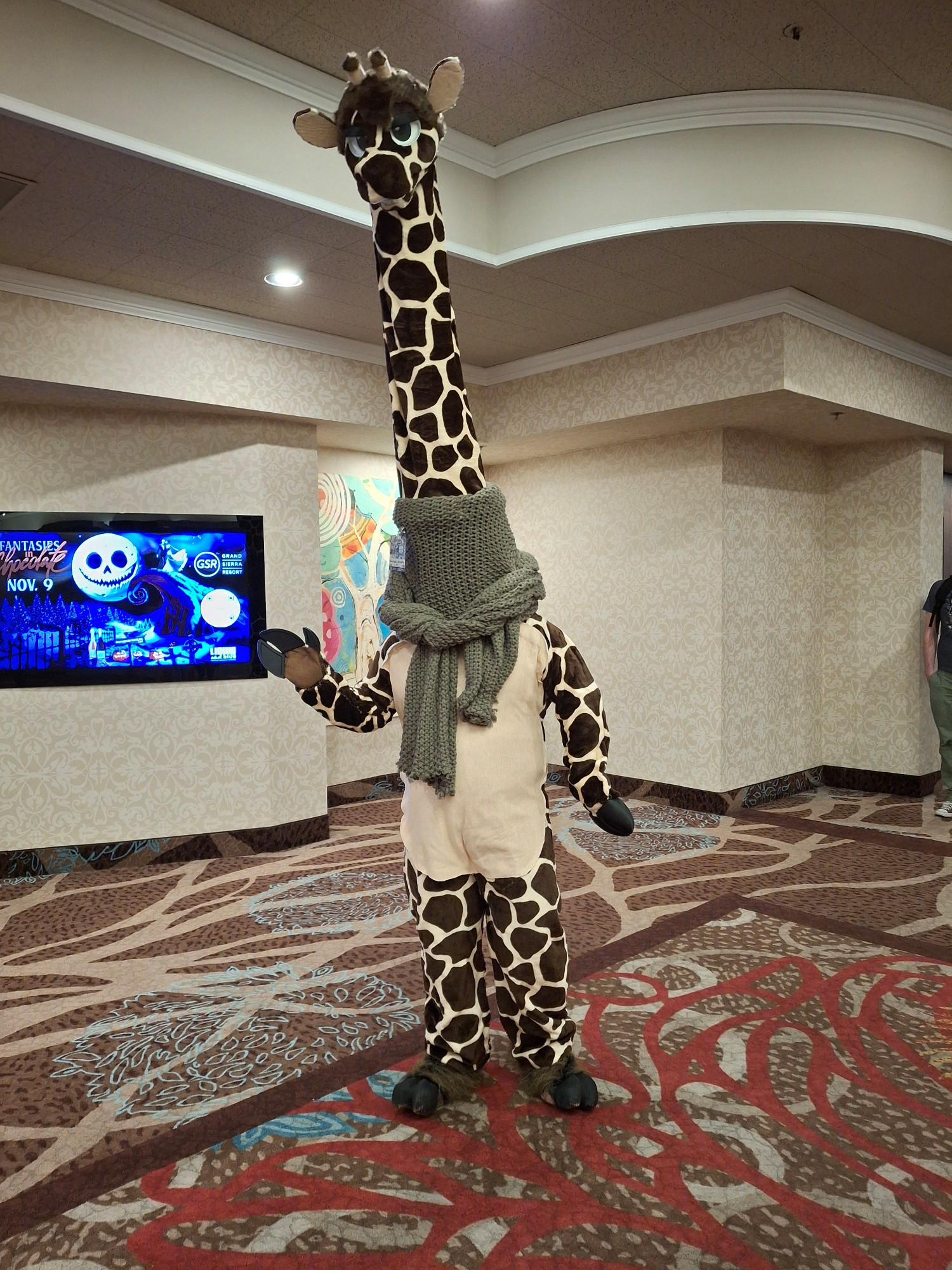 A giraffe wearing a green scarf