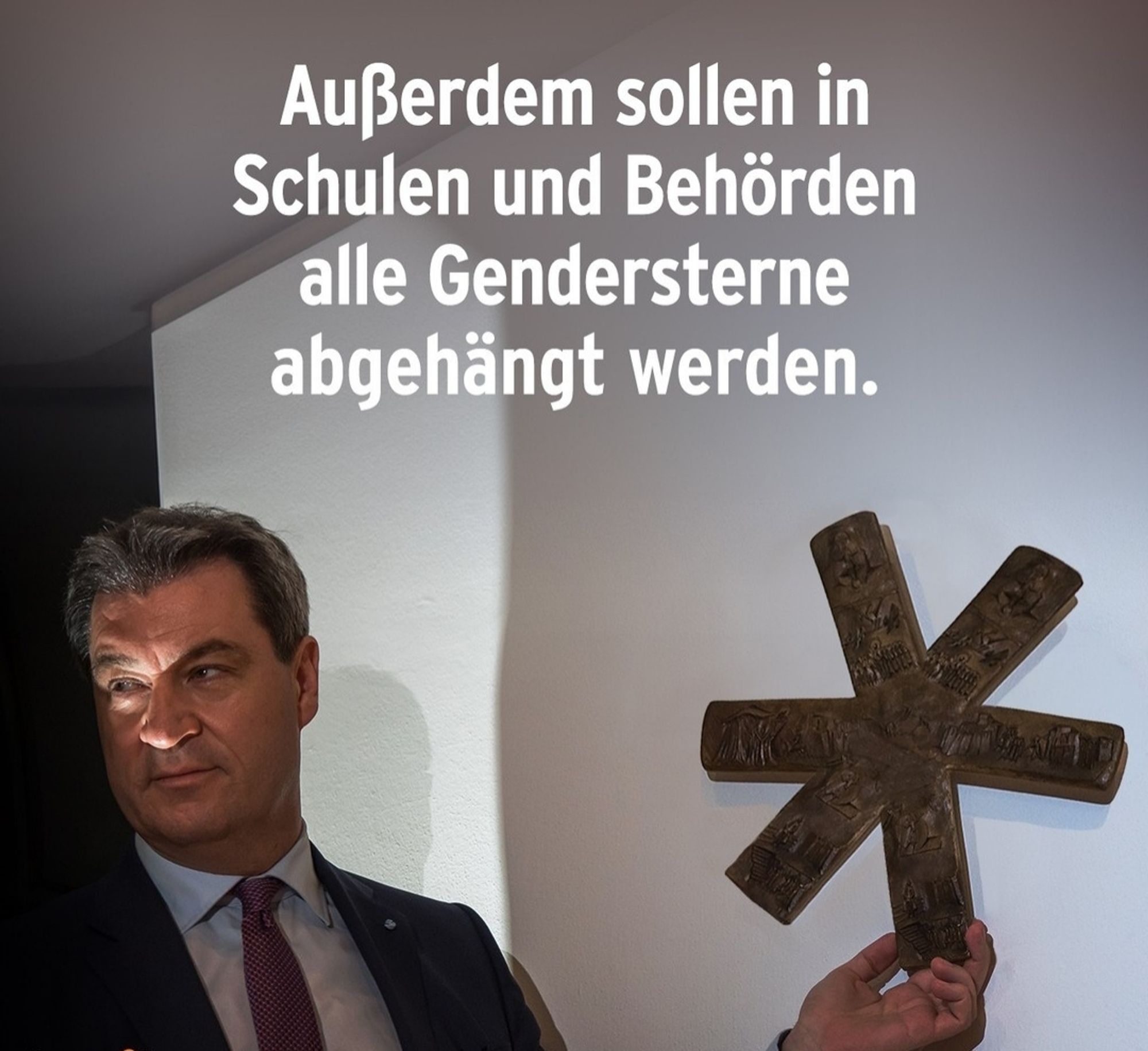 Söder hängt eine bei gruseliger Beleuchtung einen bronzenen Asterisk (mit christlichen Motiven) vor eine Wand. Hier als abgenommenes Gendersternchen interpretiert