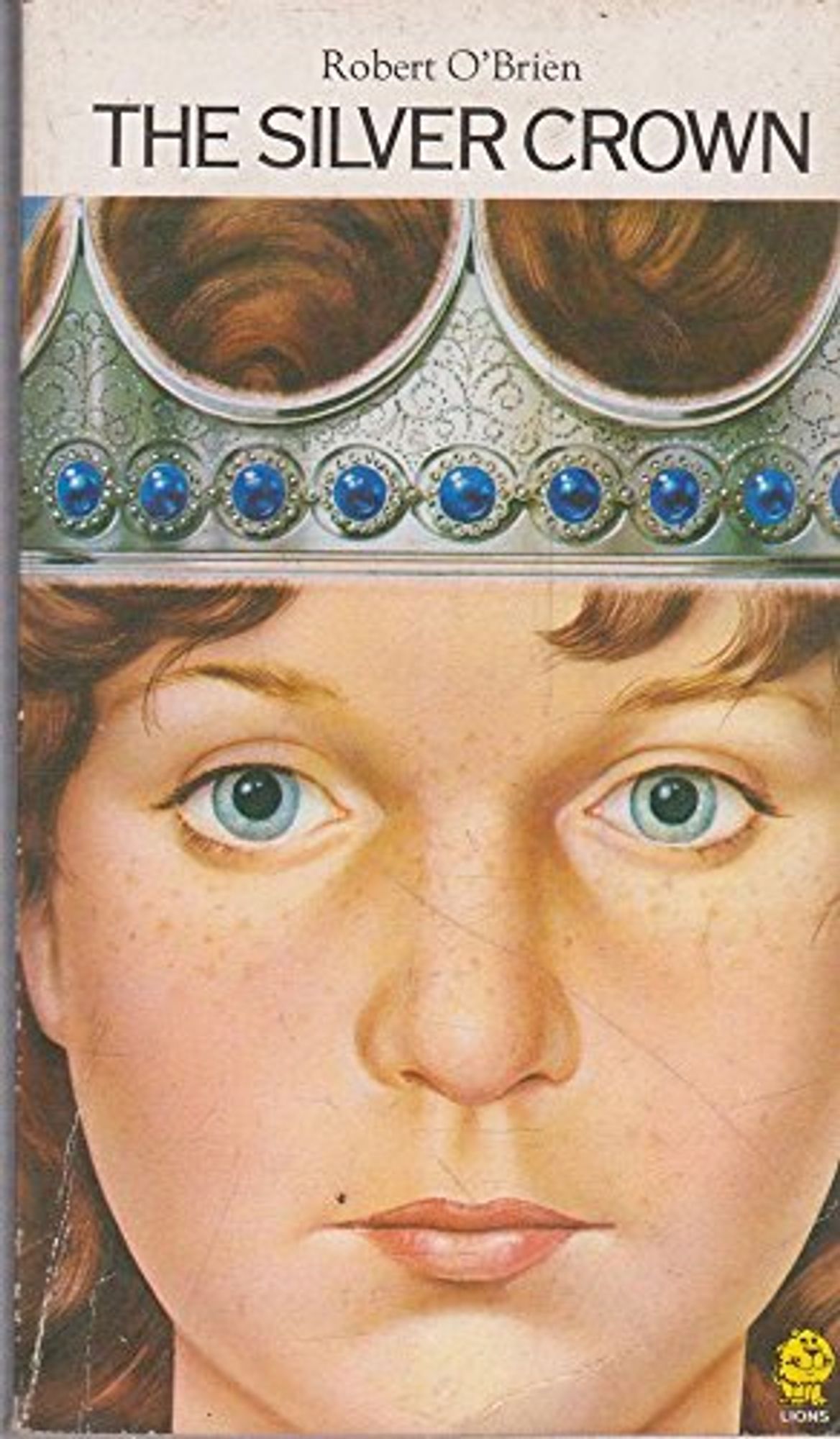 A book titled 'The Silver Crown' by Robert O'Brien. The cover is a close up drawn image of a girl's face.  Across her brow sits a silver crown with blue gemstones around the band of the crown.