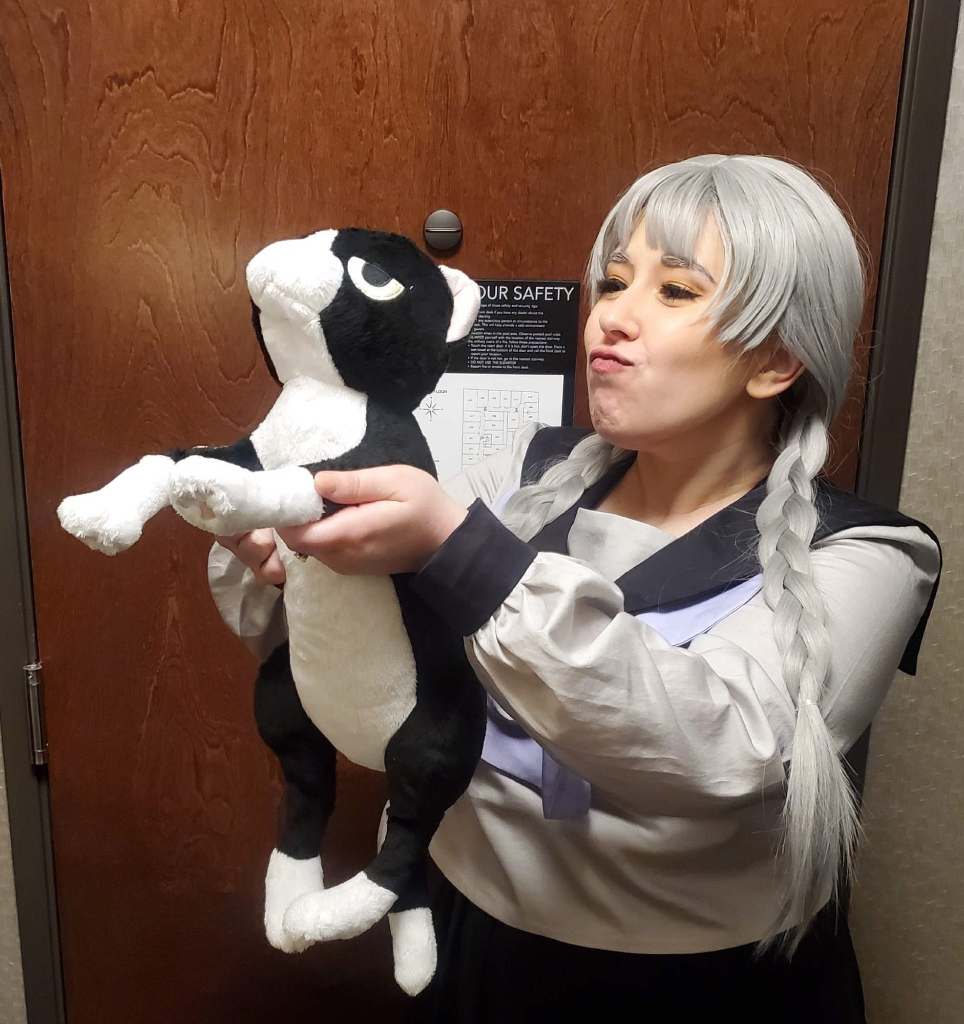 Photo of me in cosplay as the 1985 "Kiriko Douji" version of Tsukasa Okino from the video game 13 Sentinels: Aegis Rim. I'm holding up the official Atlus plush of the cat "Fluffy"/"Shintaro" from the game.