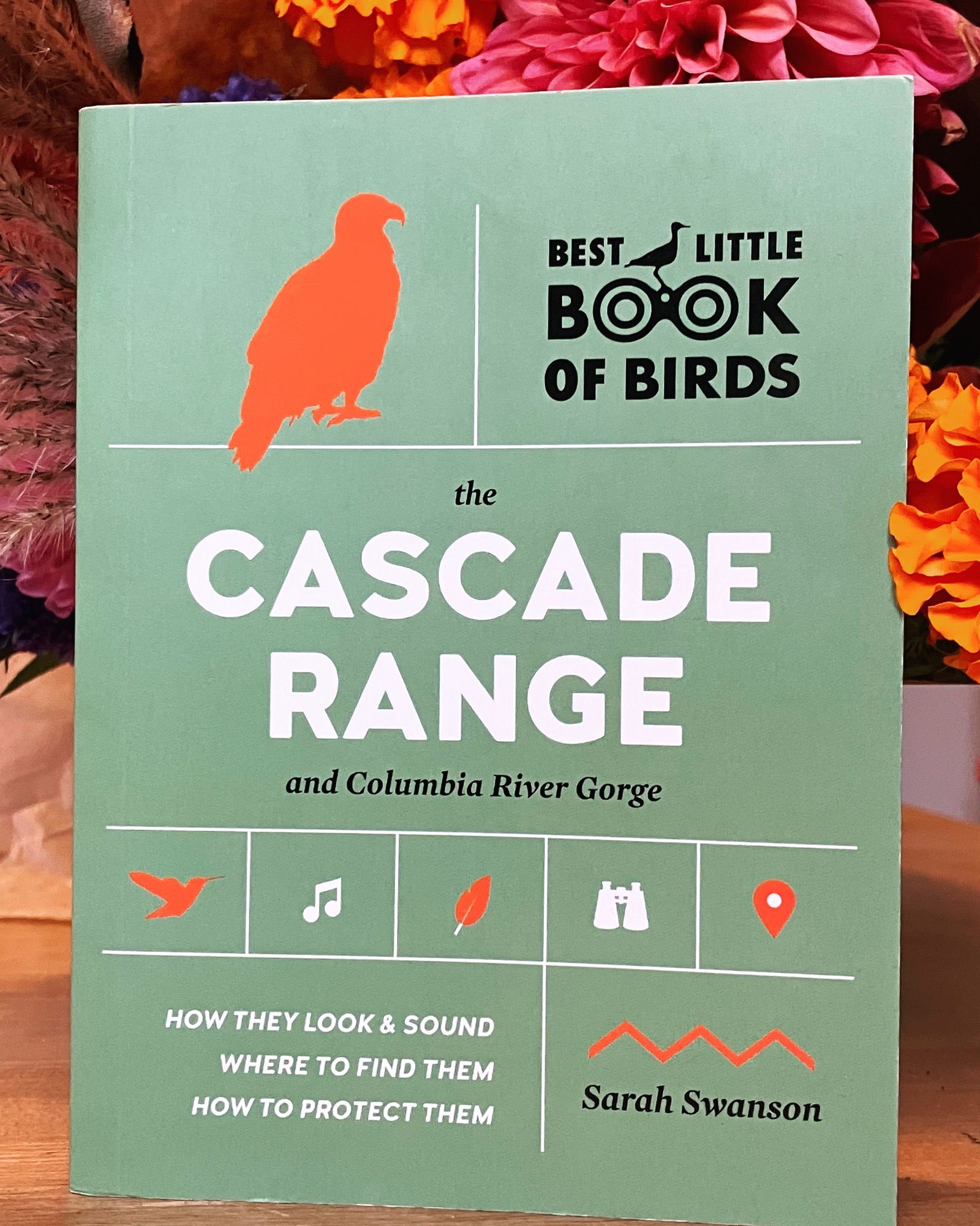 A small green book with orange and white print. Best Little Book of Birds: the Cascade Range and Columbia Gorge. By Sarah Swanson.