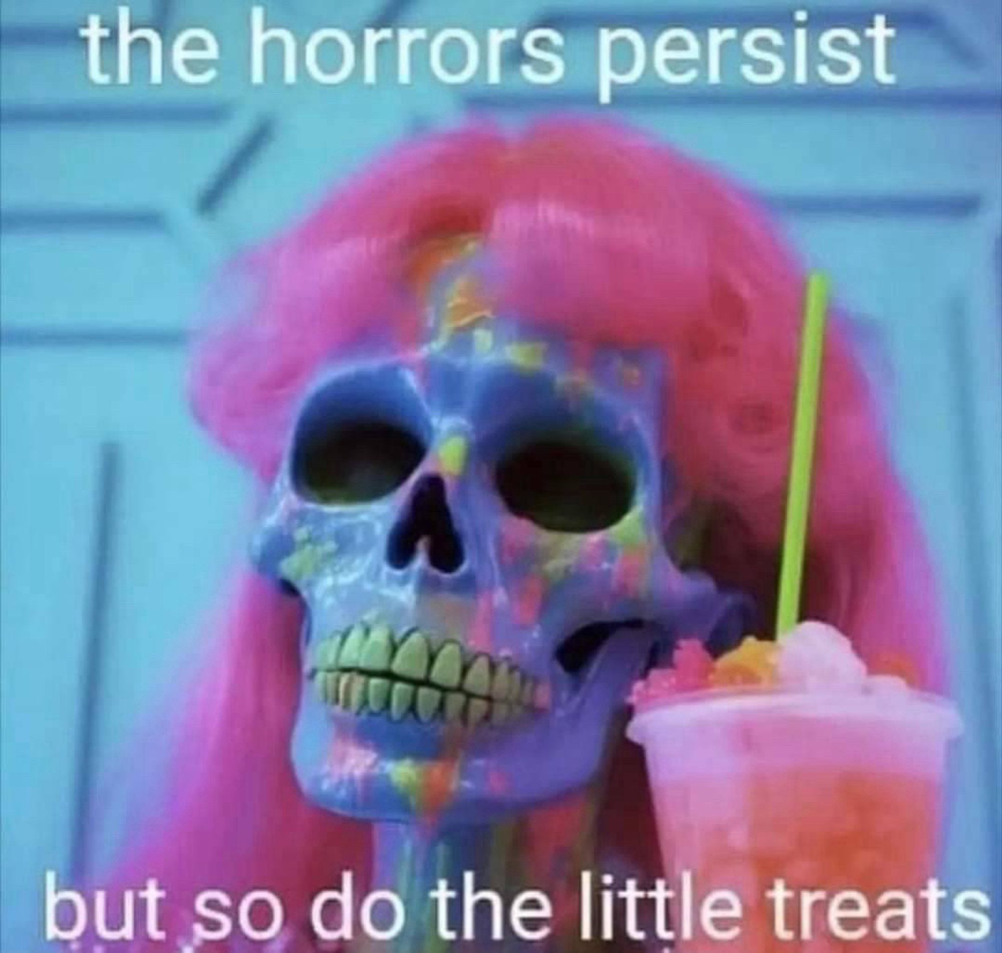 Meme photo of a multi coloured human skull with a pink wig on, holding a slushie drink. The text says “the horrors persist but so do the little treats”