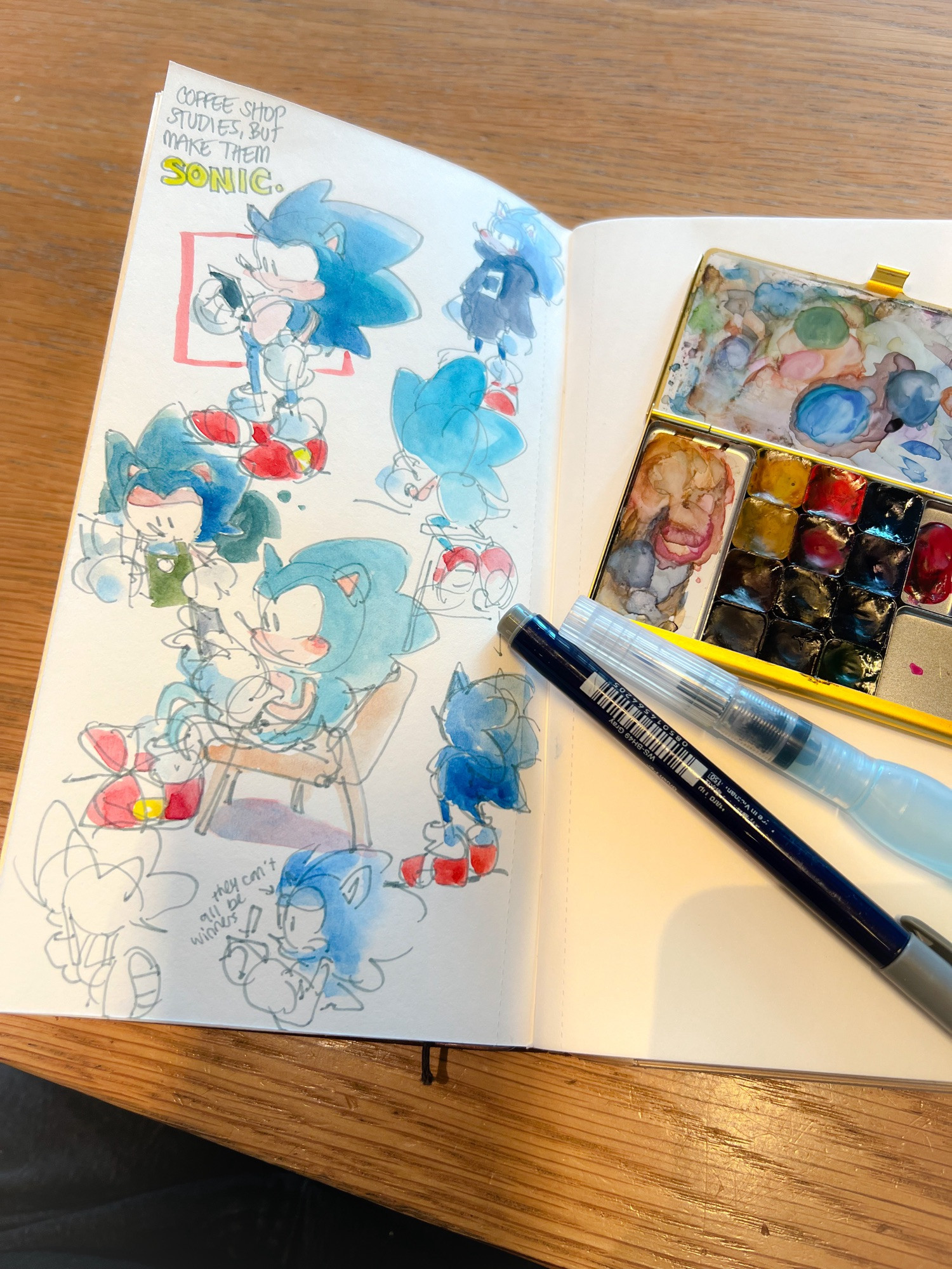 Photo of an open sketchbook with pen, waterbrush, and watercolor tin. Watercolor drawings of Sonic in various coffee shop poses. Text reads “Coffee shop studies, but make them Sonic.”