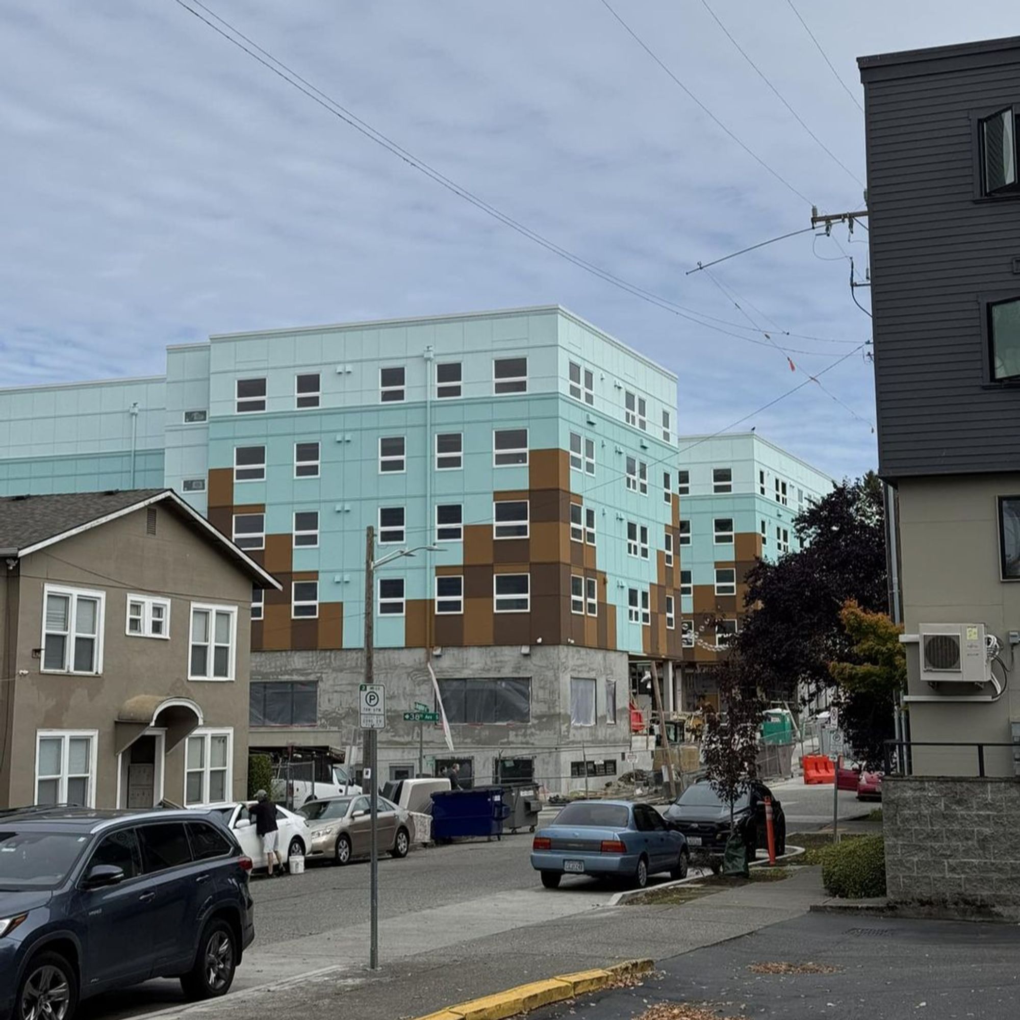 New condo/apartment building that is mostly teal but has a few large pixelated brown triangles that are maybe supposed to be pyramids? Between the color, the shape, and windows that look like eyes, it looks like poop emojis.