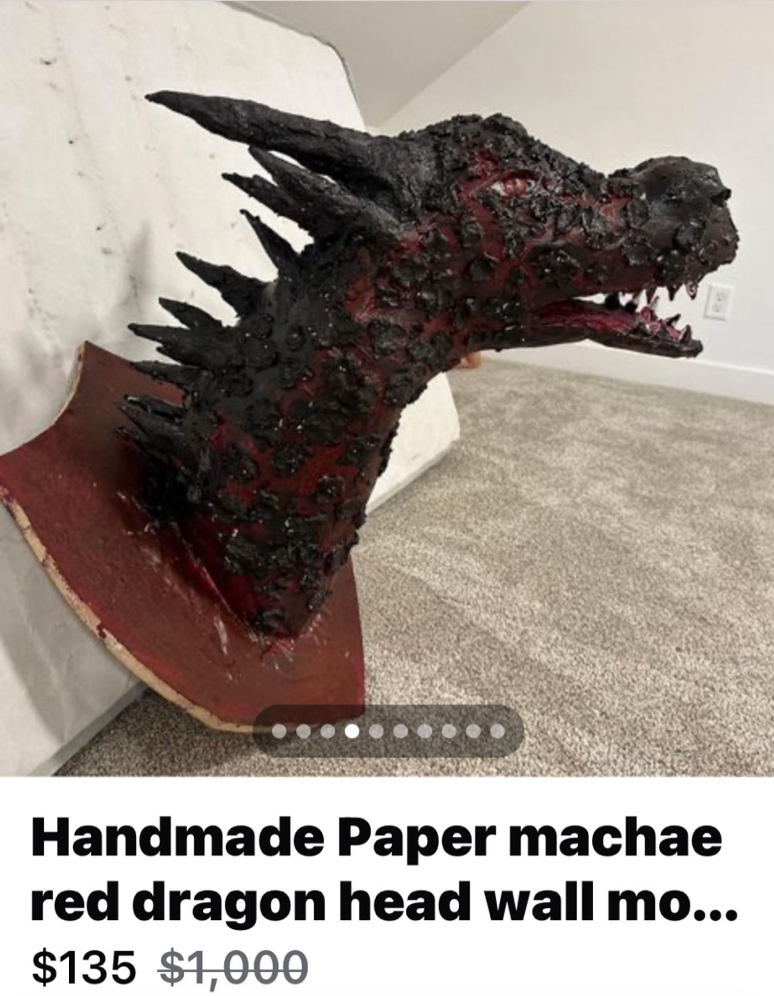 A crude papier-mâché dragon head on a wall mount being offered for the price of 135 bucks, marked down from a thousand bucks.