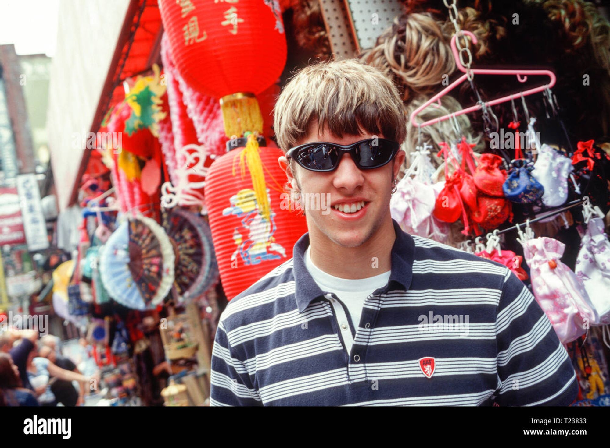 ein teenager in tyischer y2k Kleidung: gestreiftes Poloshirt und Sonnenbrille