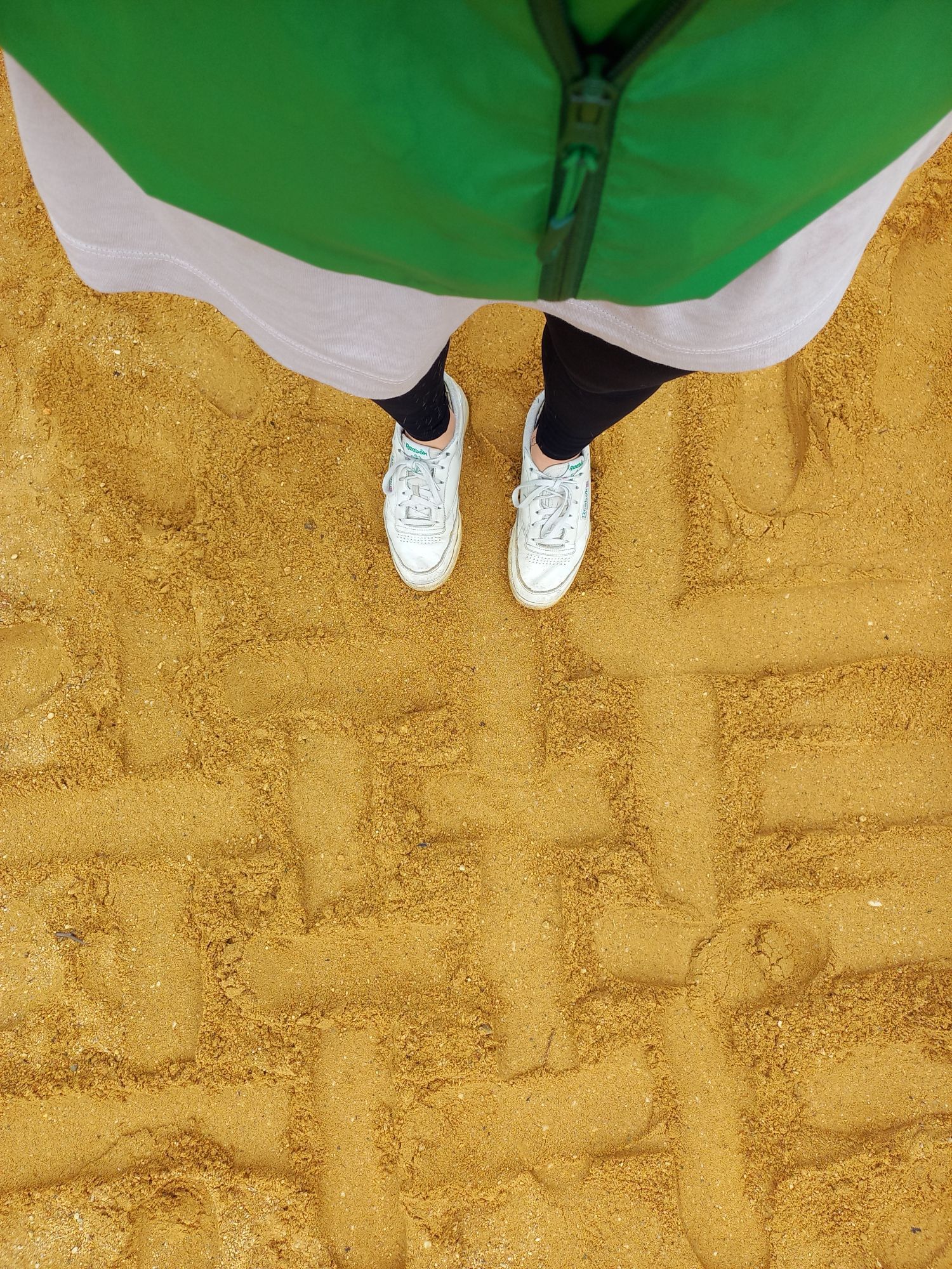 POV auf dem Sand stehend, ein Muster in den Sand getreten.