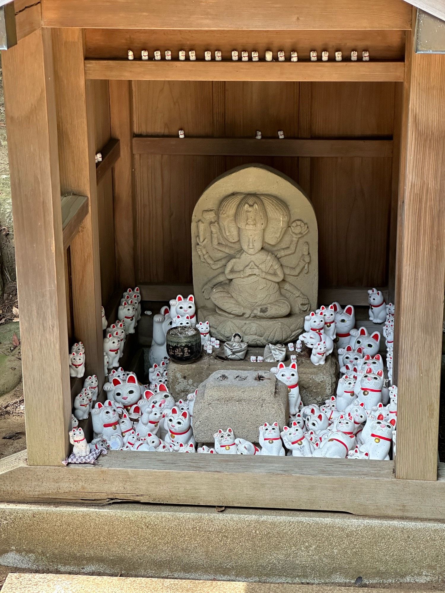 A small shrine at the Gotoku-ji temple in Tokyo, filled with tiny adorable white and red cat figures.