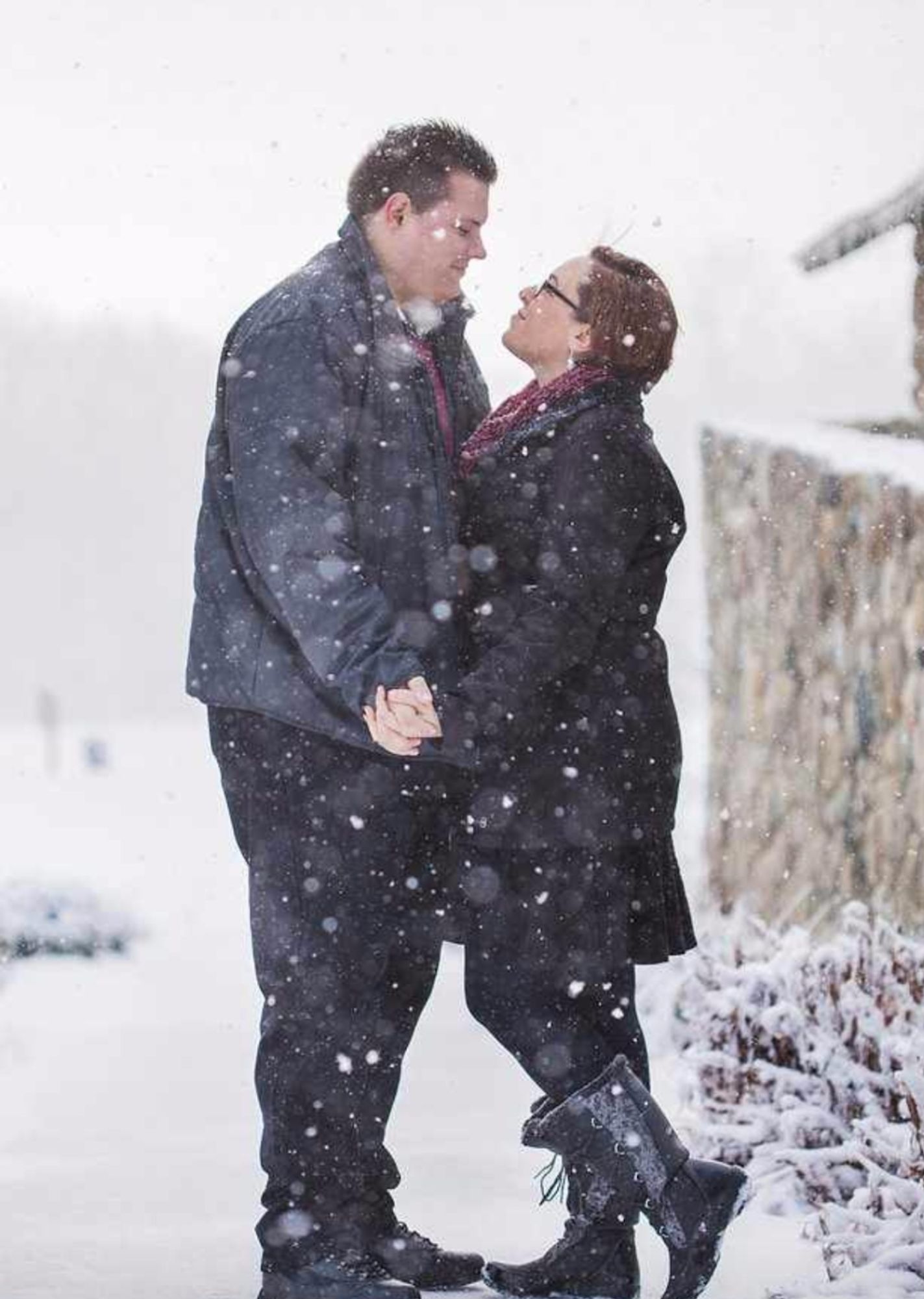 One of our engagement photos, taken in the snow as we stand holding hands and looking at each other