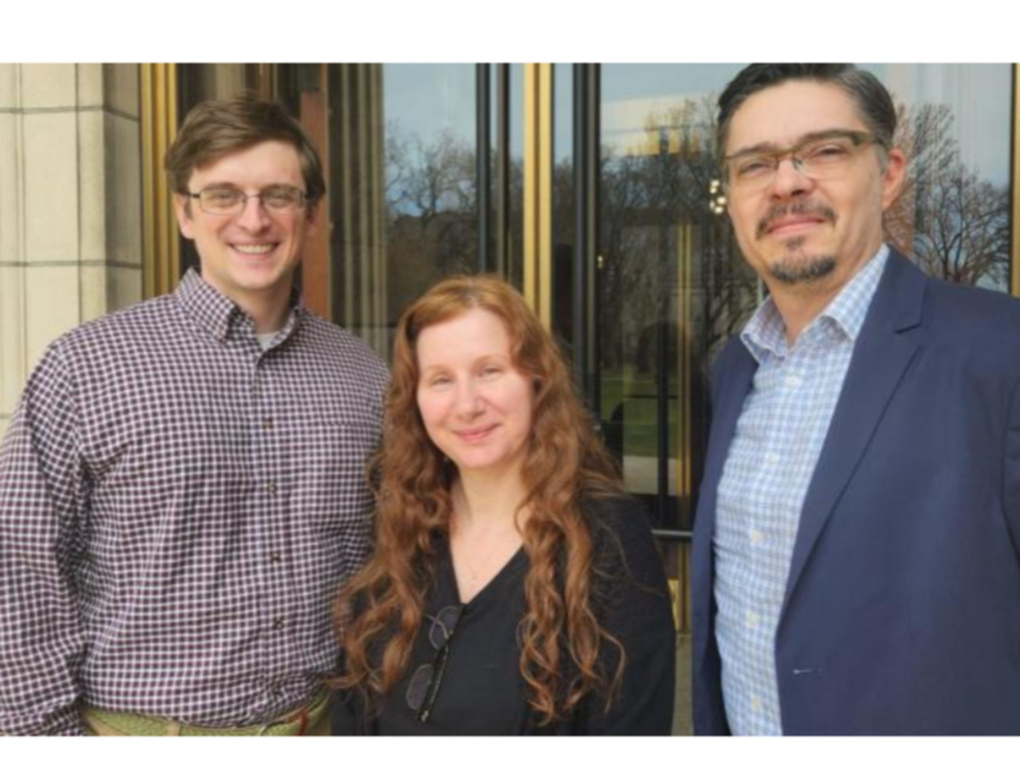 The image shows three JCB staff members -Mark, Cheryl and José- standing at the entrance to the JCB.