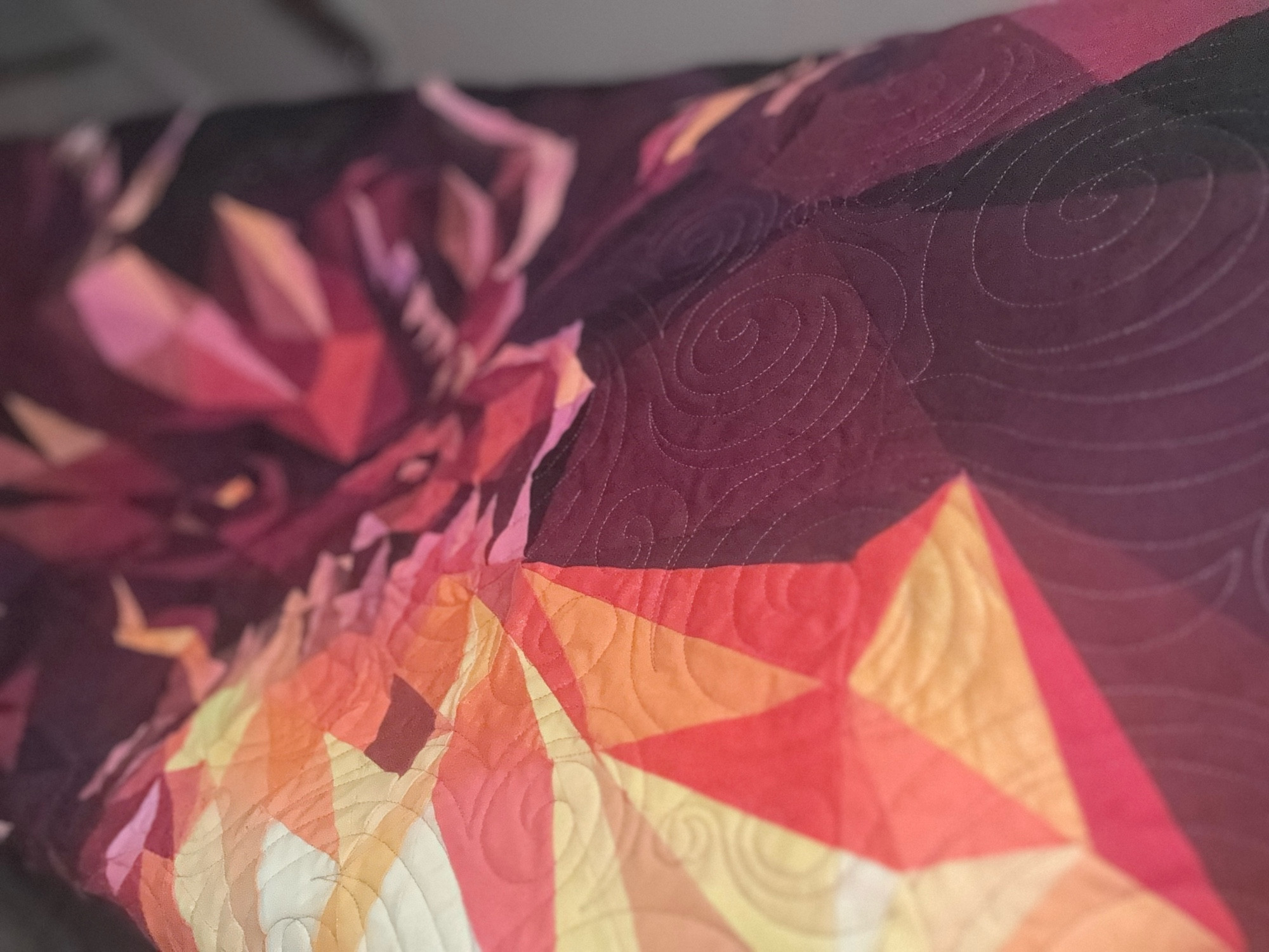 Close up of a quilt of a red dragon belching fire