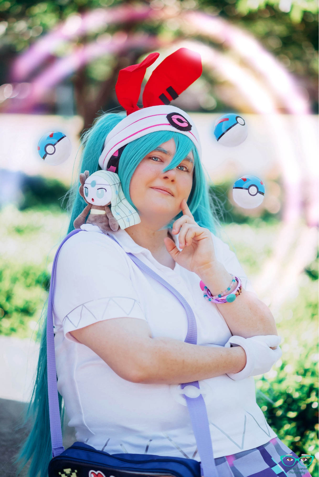 A close up of the cosplay with a Meloetta plush and floating great balls.