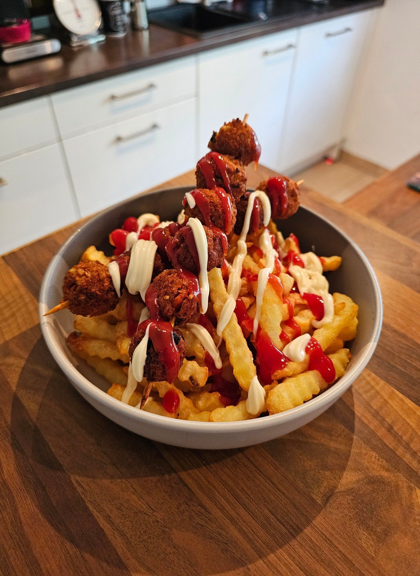 Auf dem Teller befinden sich Pommes frites, vegane Haferbällchen, Ketchup und Mayonnaise.