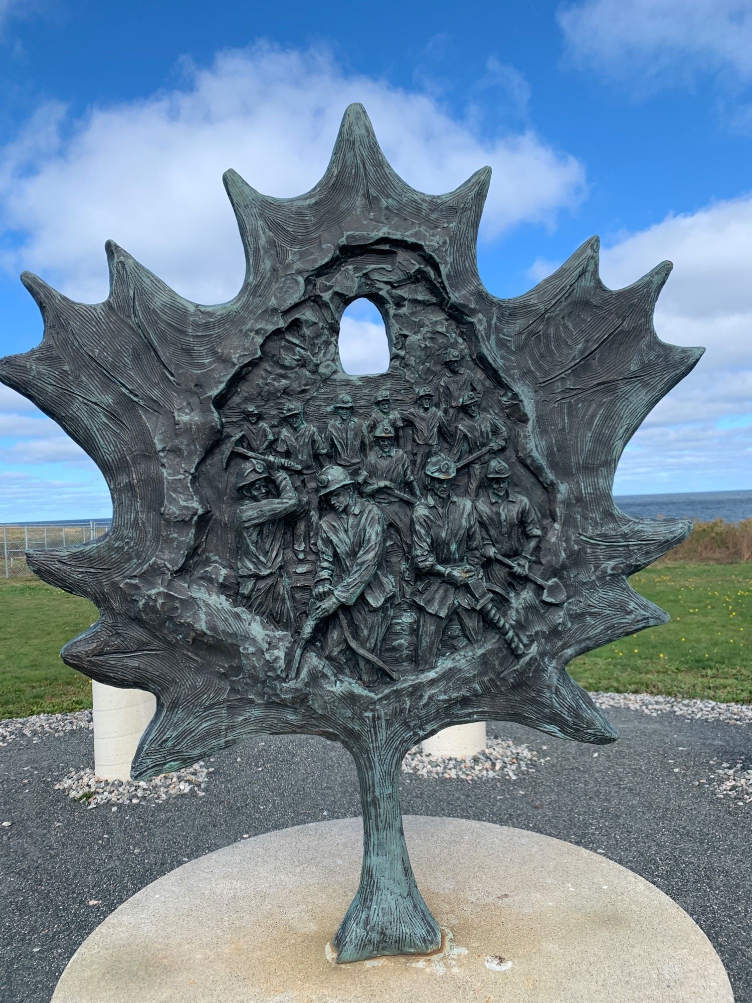 Centrepiece of the Miners’ Memorial is sculpted in bronze by Timothy P. Schmalz in a maple leaf shape. This side shows the 12 miners who died underground. The hole at the top is like the light shining through the top of a mine.