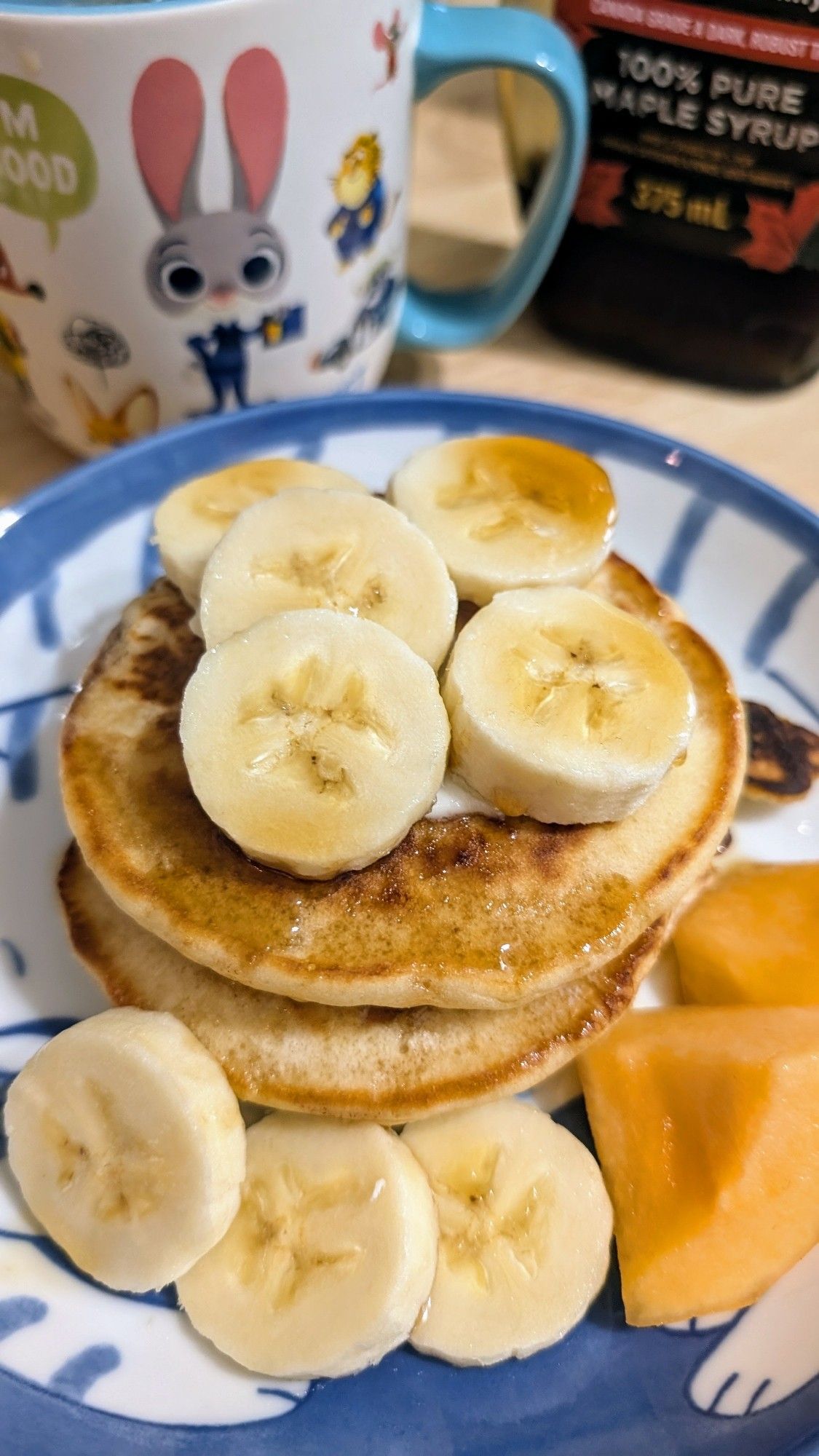 Stack of pancakes with banana slices and maple syrup.