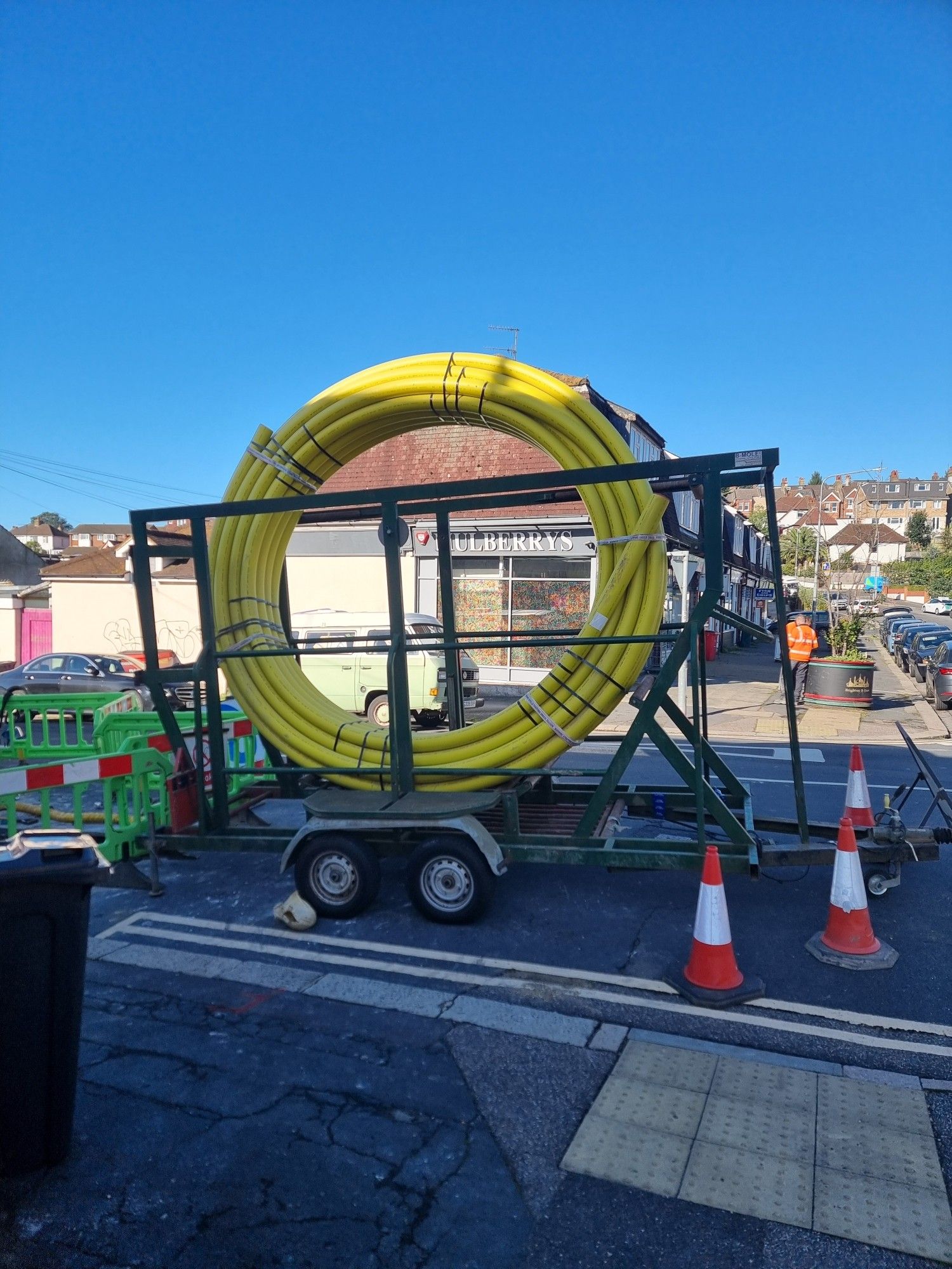 Large yellow gas pipe wound on a huge circular frame ready to be put into the ground in a local street. Looks like a giant's garden hose