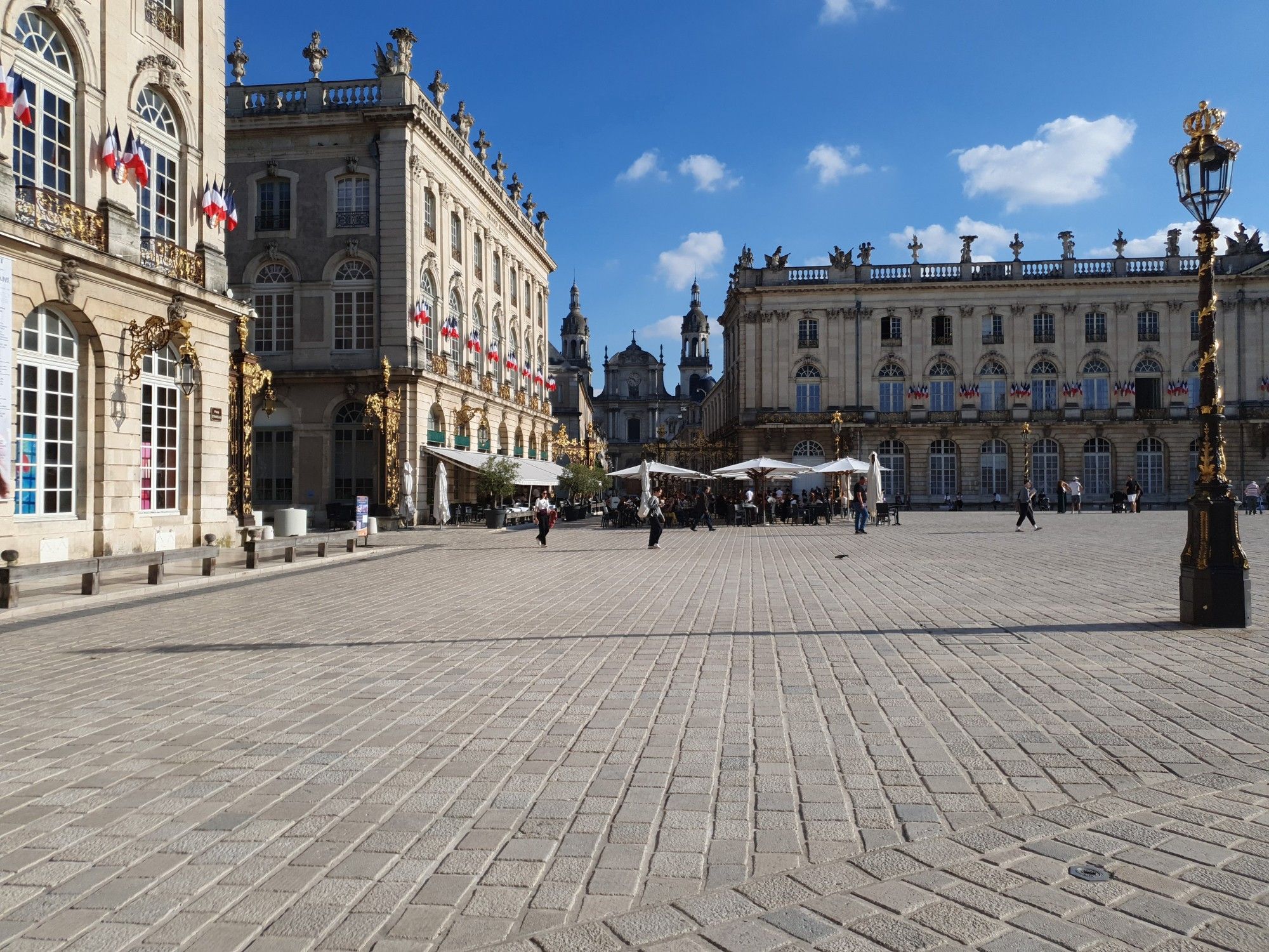 Blick über den Place Stanislas in Nancy in Richtung des südöstlichen Tors Mitte September 2024. Im Hintergrund des Tors ist die Cathédrale Notre-Dame-de-l’Annonciation de Nancy zu erkennen.