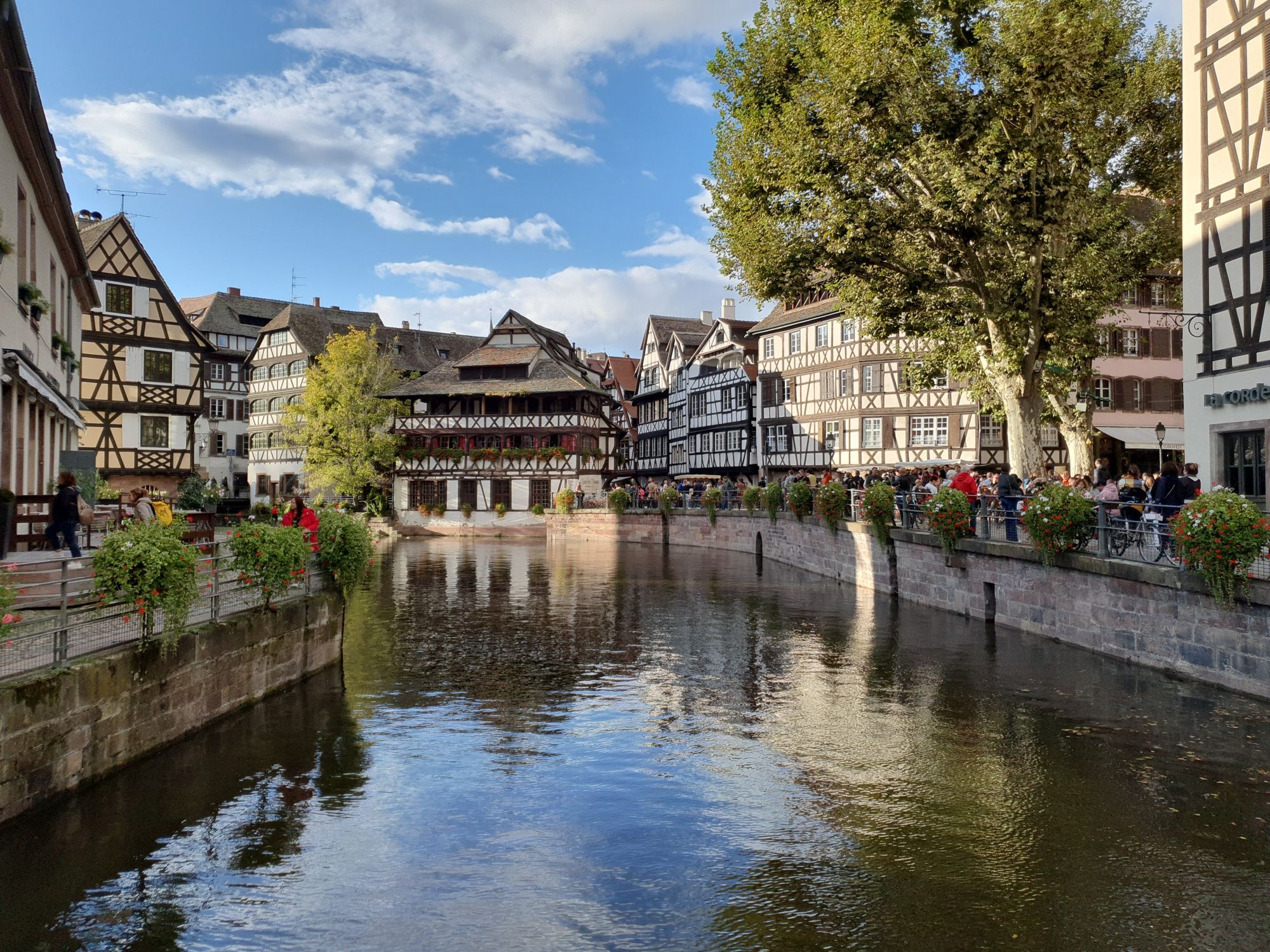 Blick über die kanalisierte Ill in das Stadtviertel La Petite France, u.a. auf das Maison des Tanneurs in der Bildmitte und den Place Benjamin-Zix in der rechten Bildhälfte Ende September 2024 gegen Abend.