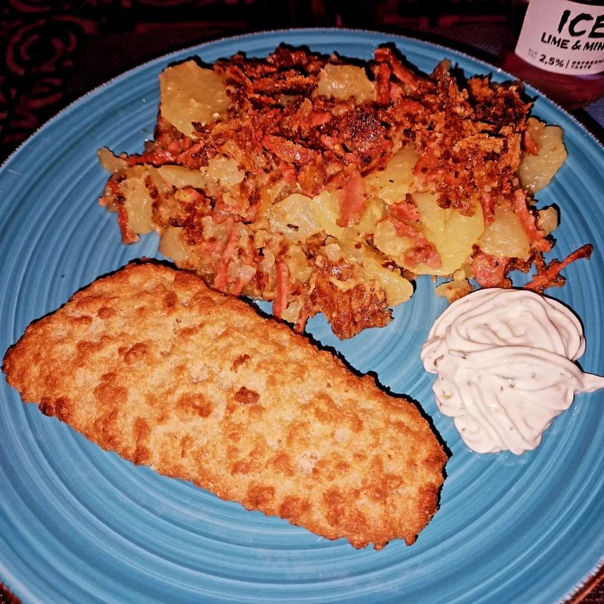 Ein blauer Teller mit Bratkartoffeln, Backfisch und Remoulade