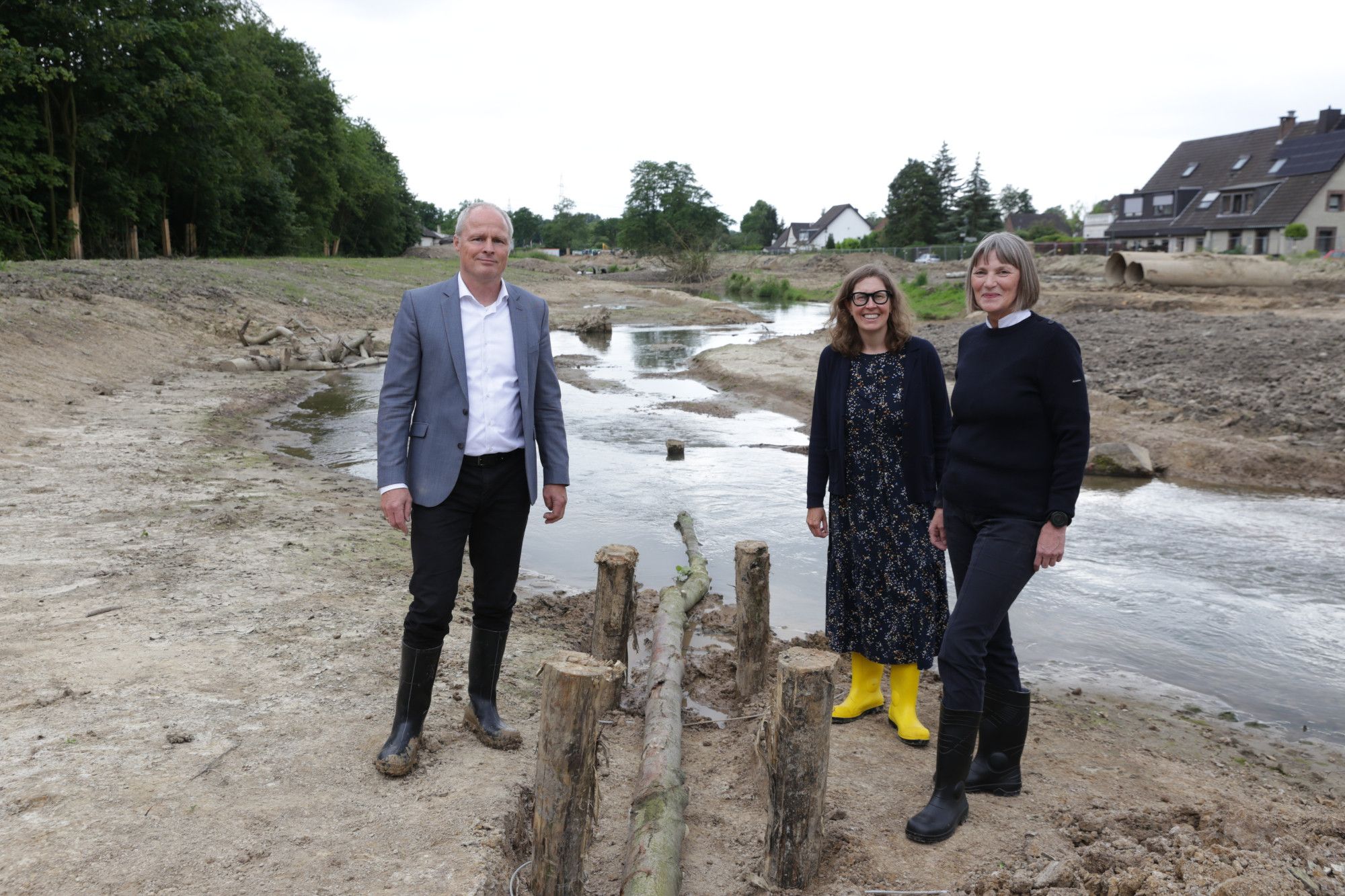 Stadtkämmerin Dorothée Schneider, Janine Mentzen, kaufmännische Betriebsleiterin des SEBD, und Frank Heuner, technischer Betriebsleiter des SEBD, stehen auf dem Baufeld an der Südlichen Düssel in Vennhausen und schauen für ein Gruppenfoto in die Kamera.